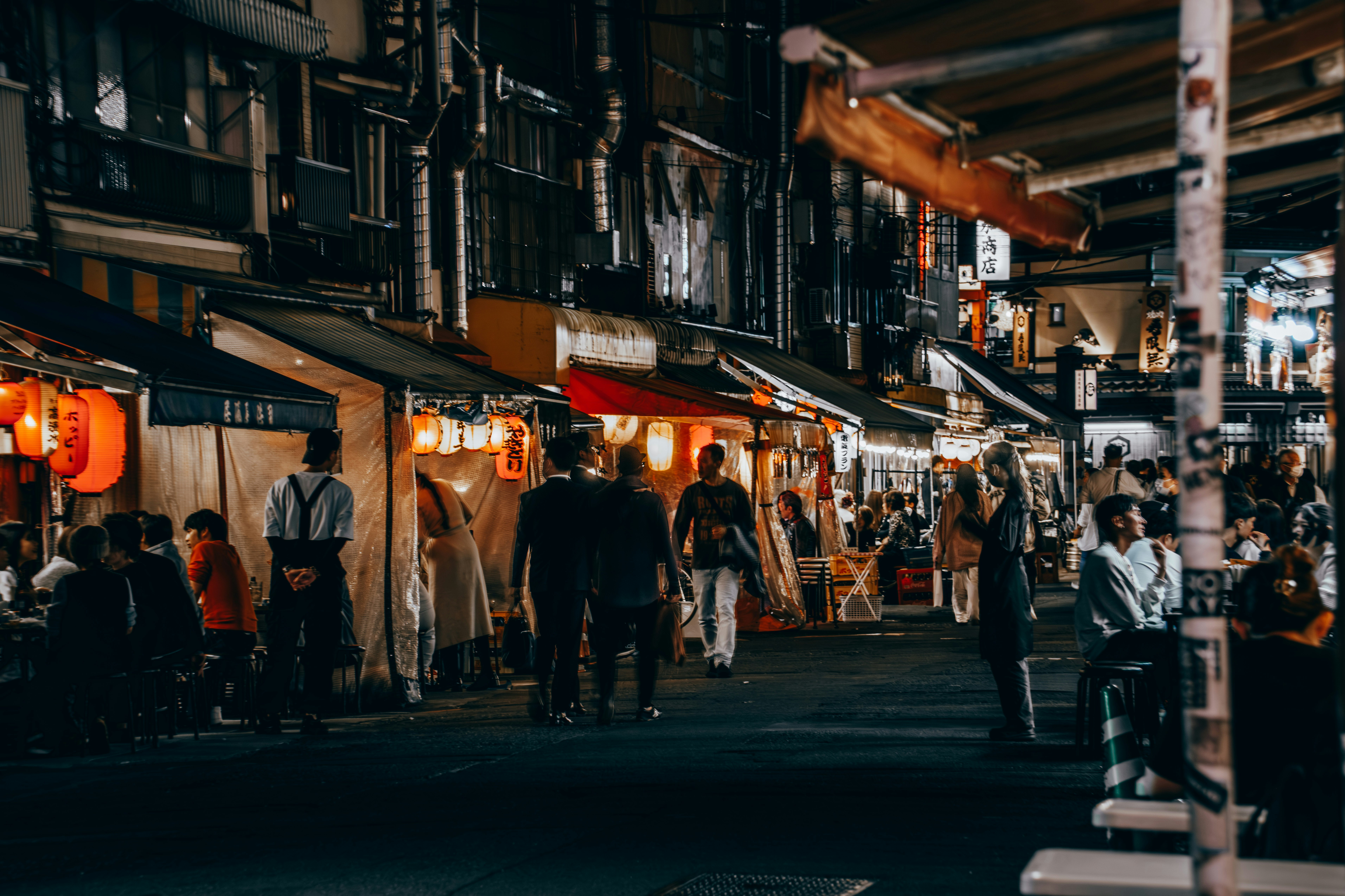 Scena notturna di un mercato di strada giapponese con persone che camminano e lanterne colorate