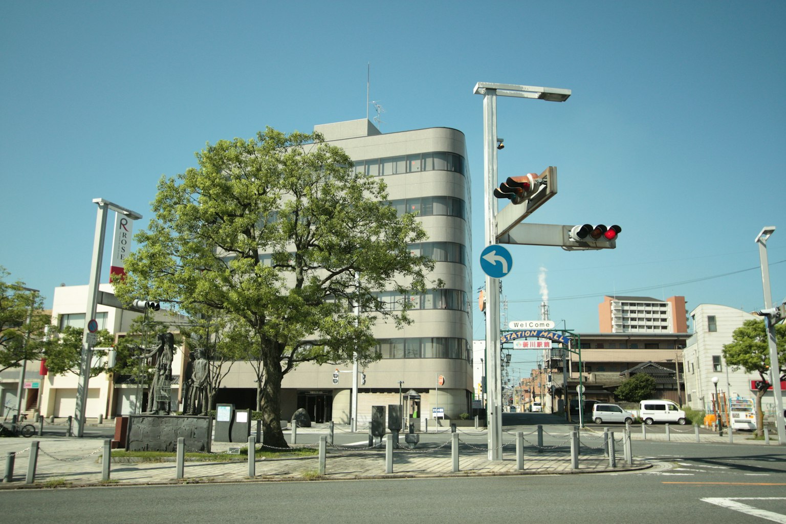 Modern building at an intersection with traffic lights under a clear blue sky