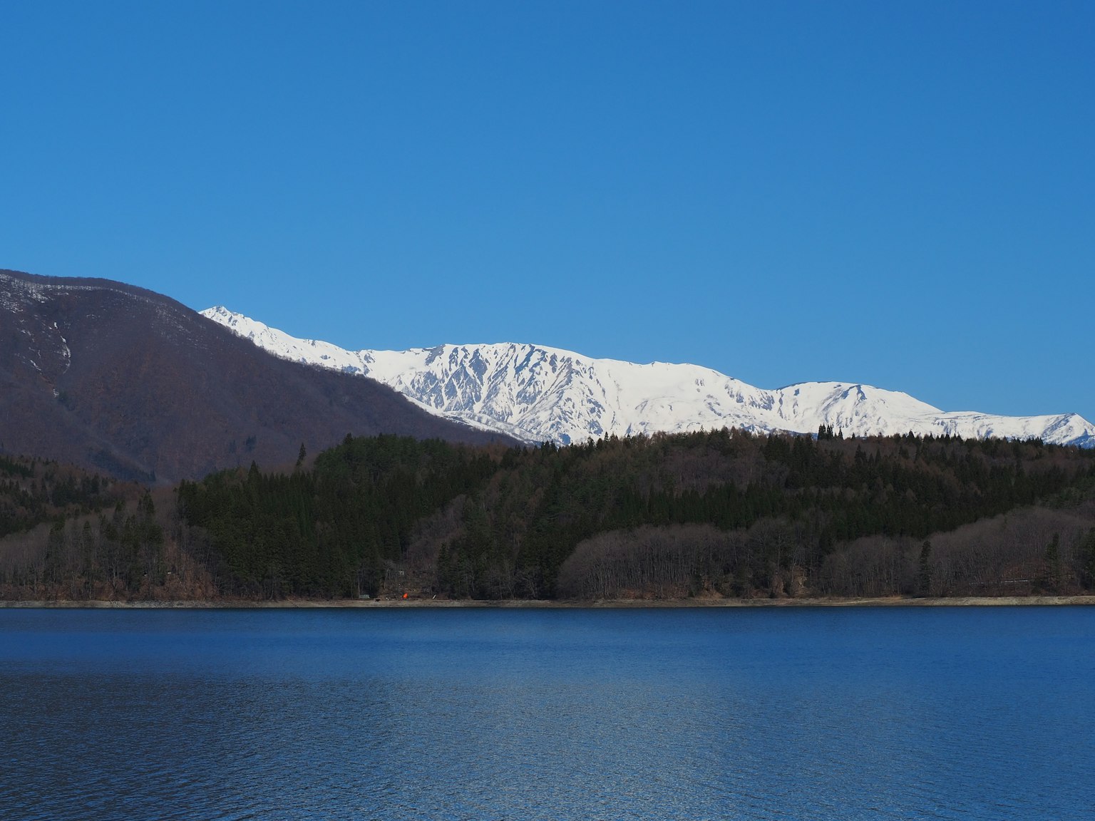 Vista panoramica di un lago con montagne innevate e cielo blu