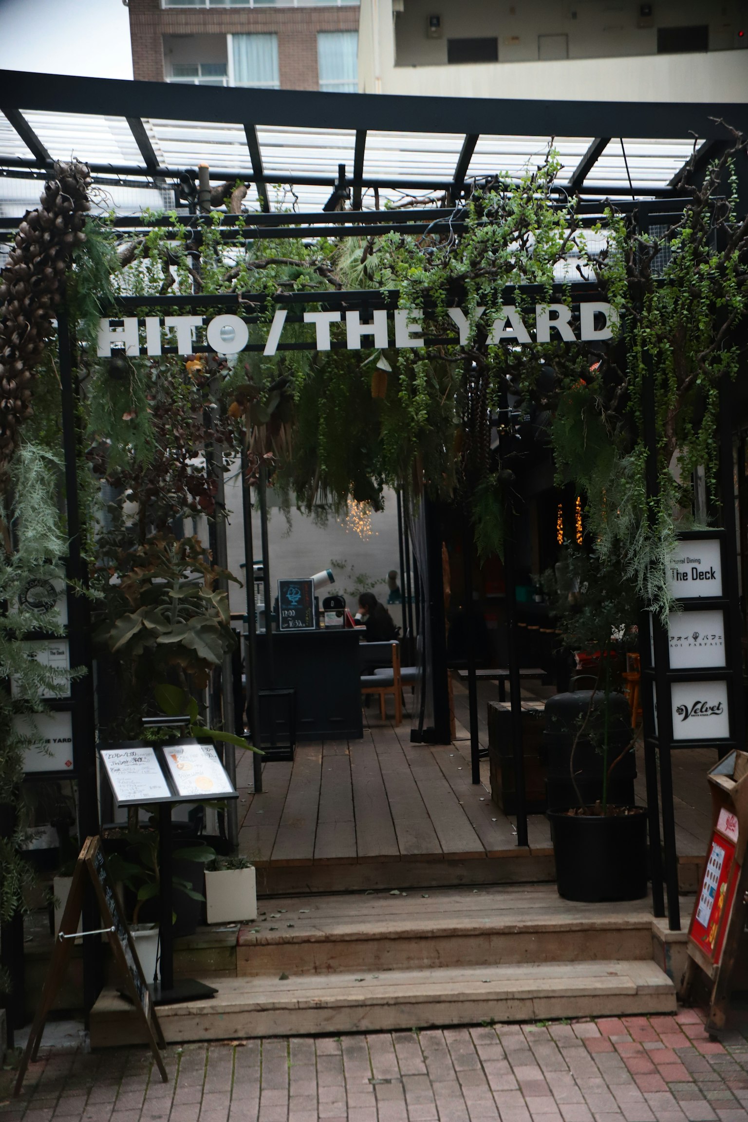 Eingang zu einem Café umgeben von Grün mit dem Schild HITO / THE YARD