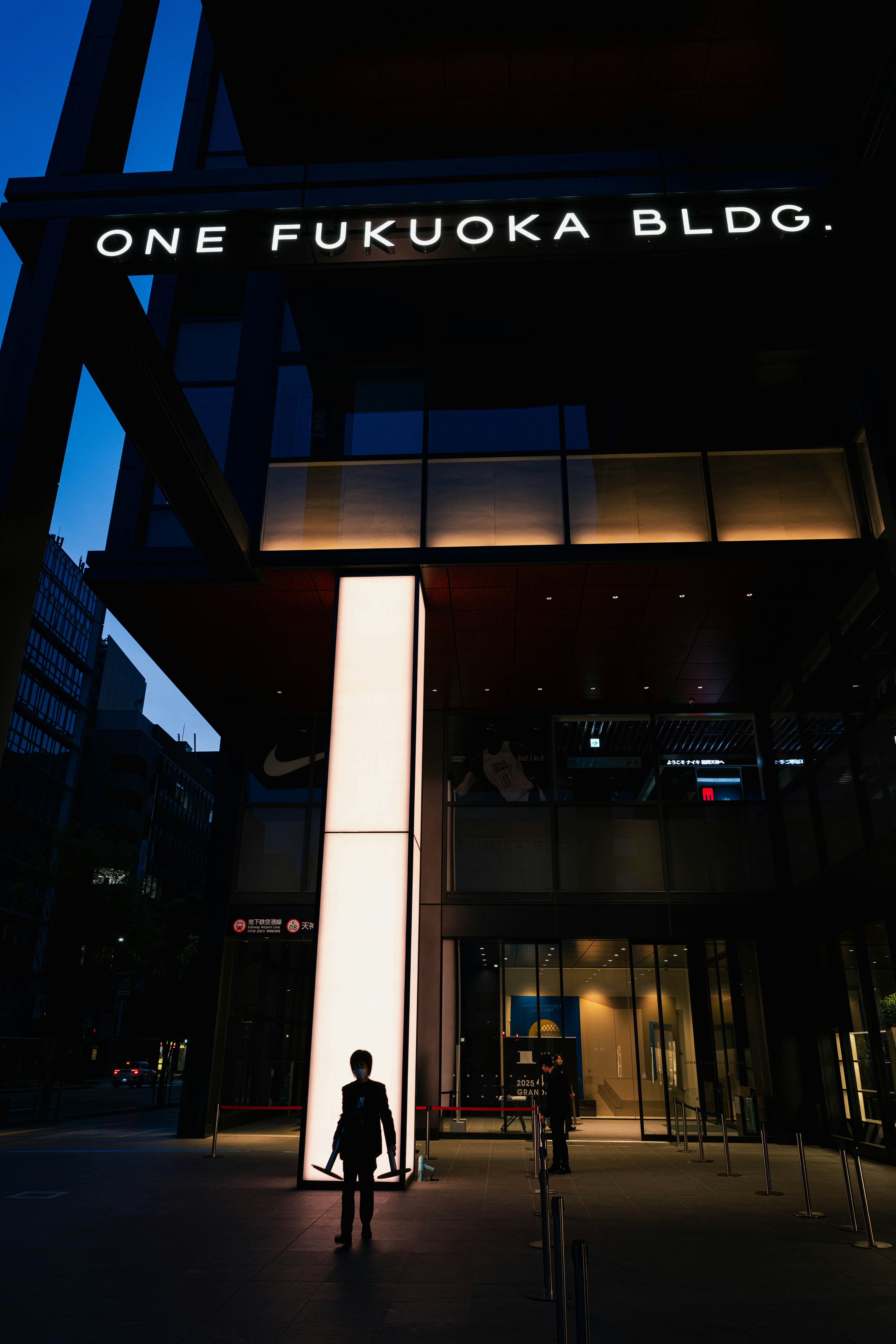 ผู้คนเดินหน้าทางเข้าตอนกลางคืนของ ONE FUKUOKA BLDG.