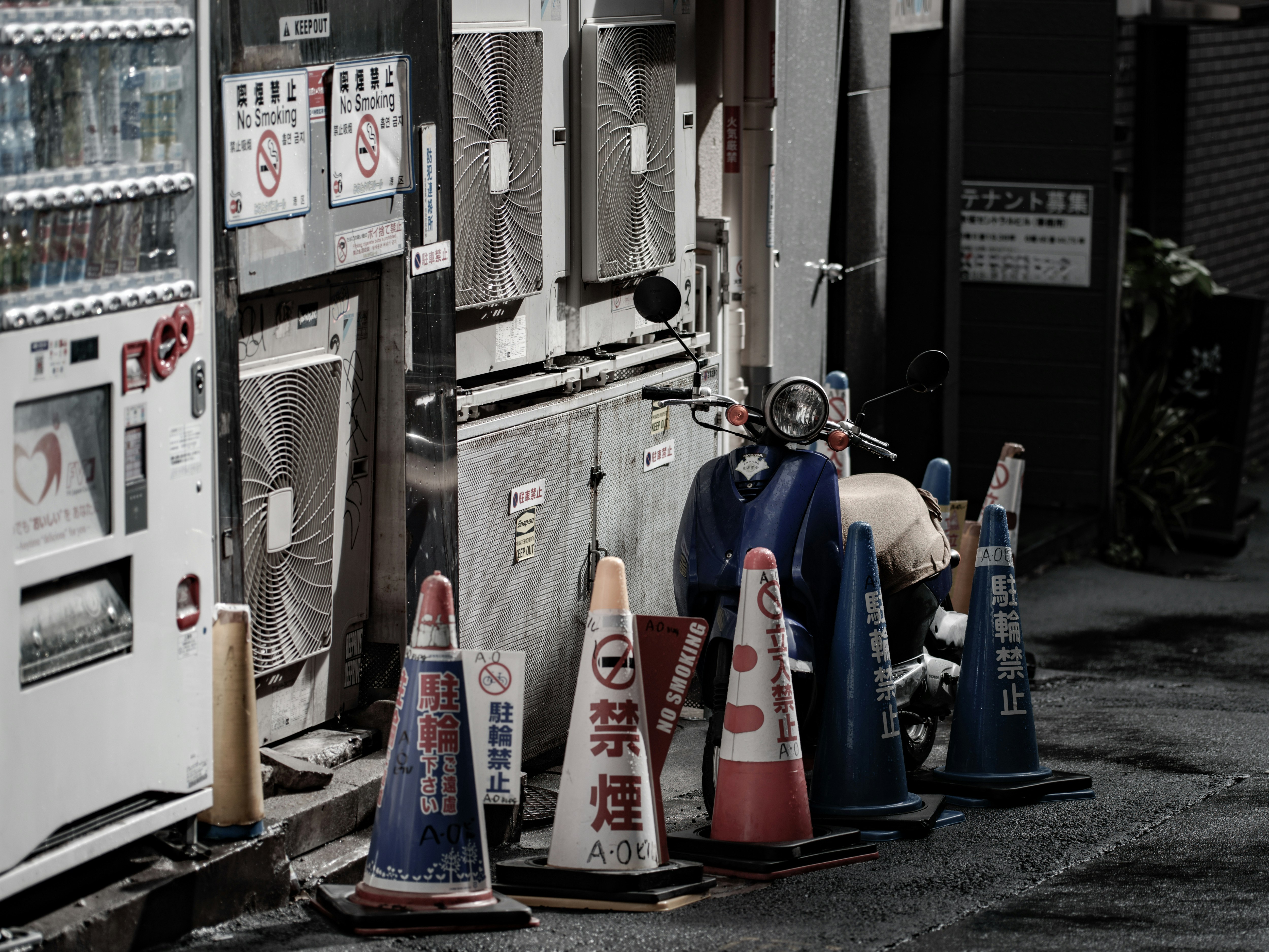 雨上がりの路地で並ぶ原付バイクとコーンのある街角