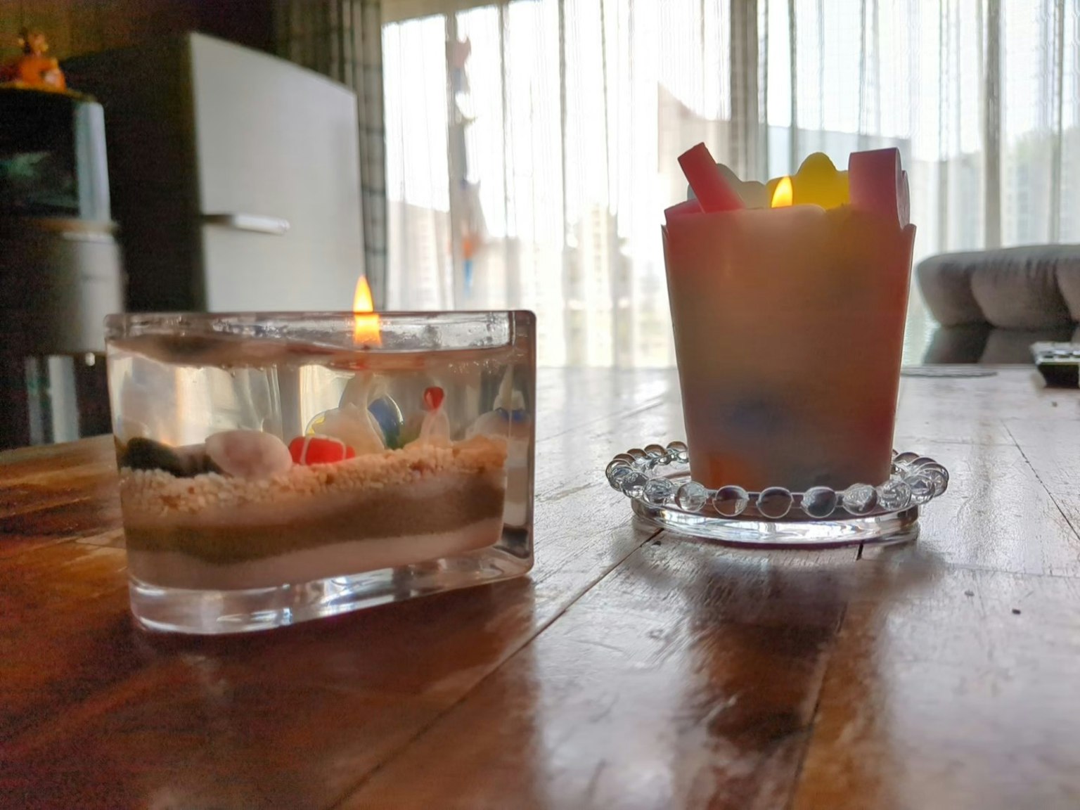 Transparent candle and colorful candle on a wooden table