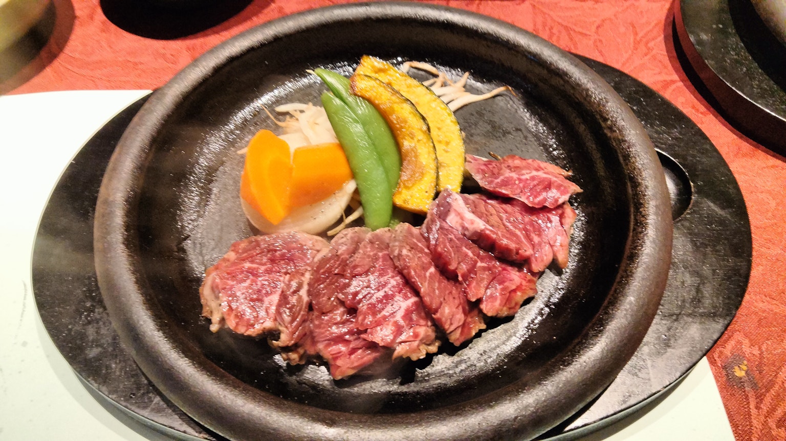 Dish of grilled meat and vegetables served on a hot plate
