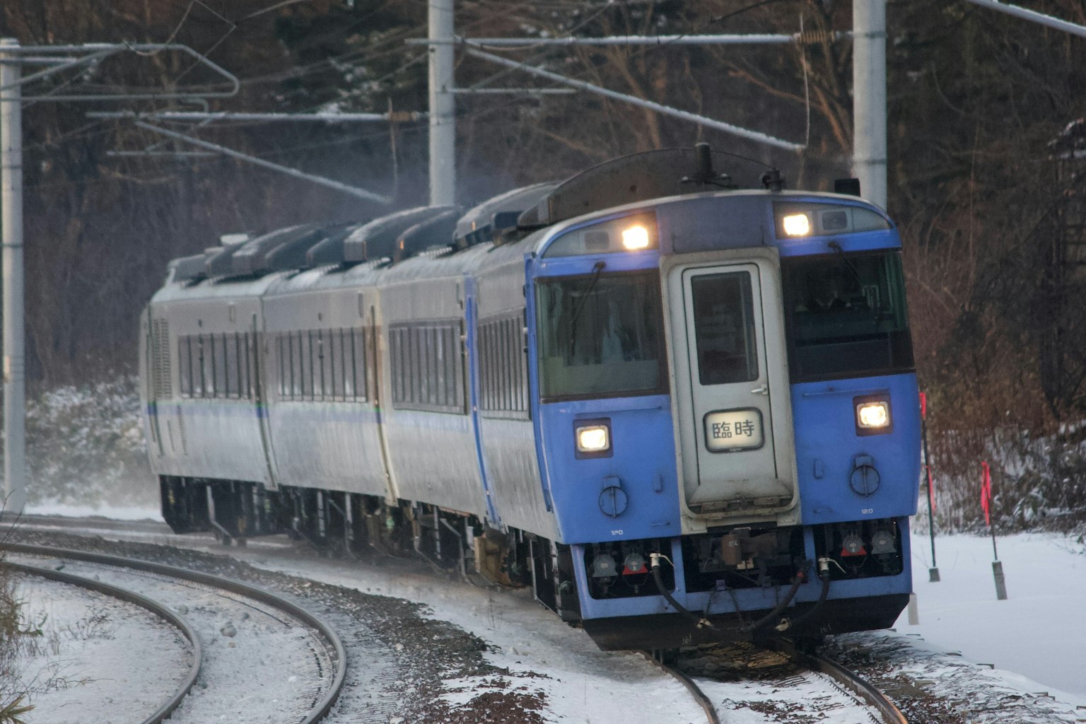 รถไฟสีน้ำเงินที่วิ่งผ่านโค้งที่มีหิมะ