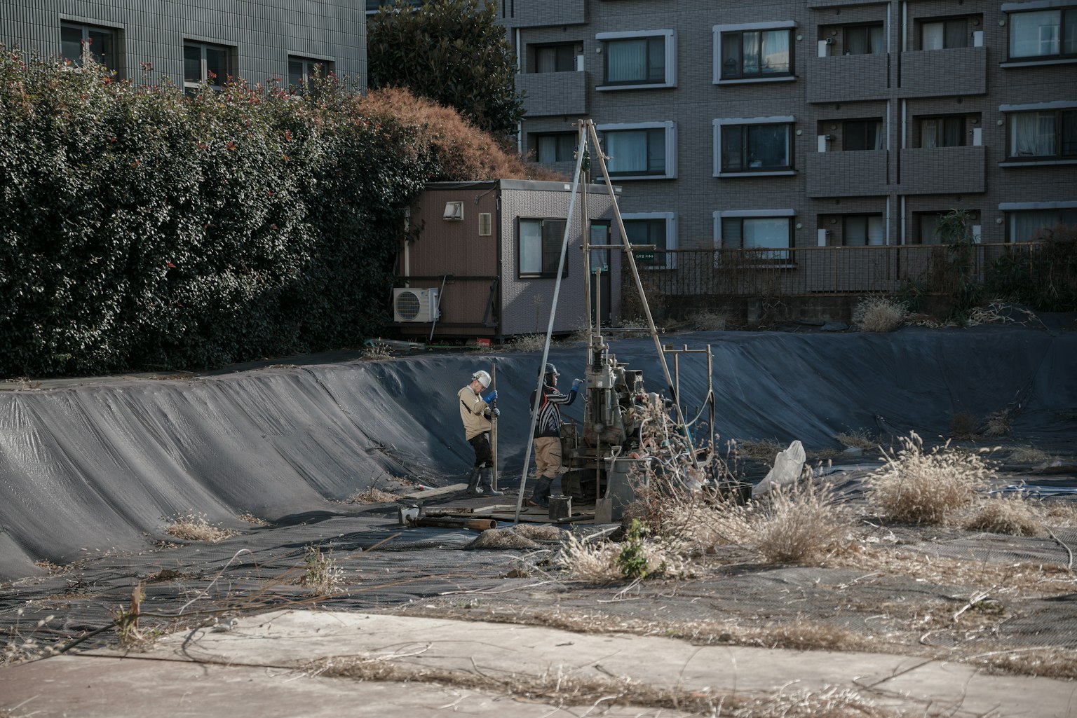 People working in an empty lot surrounded by buildings