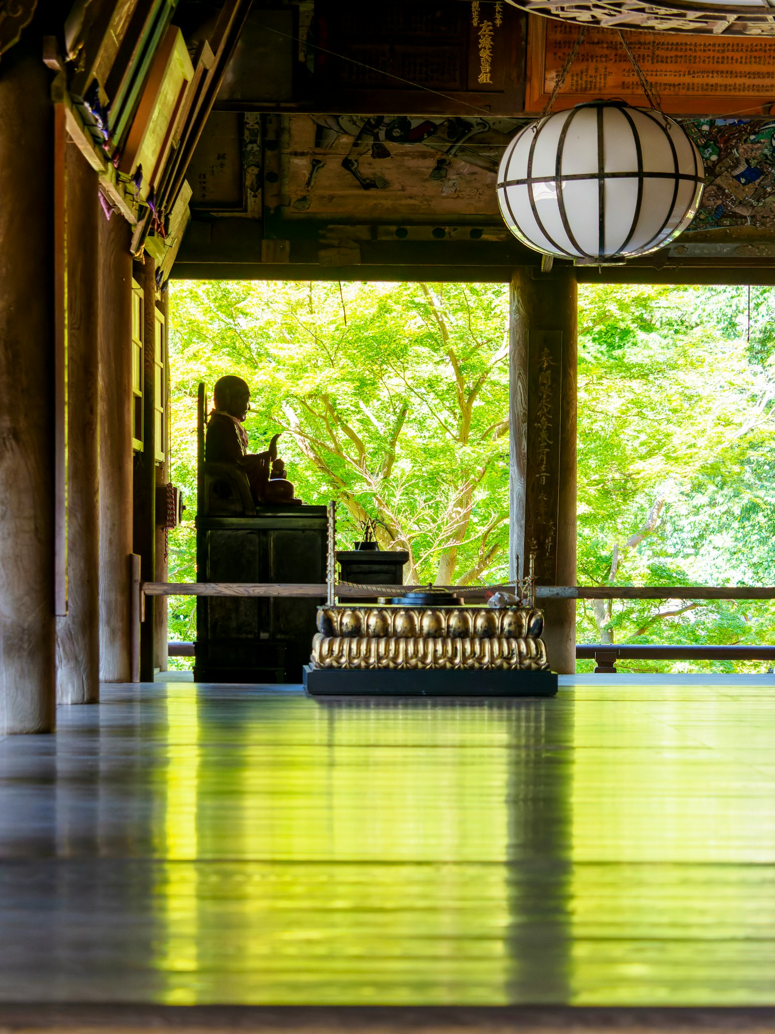 寧靜佛教寺廟內部，有坐著的佛像和綠色樹葉
