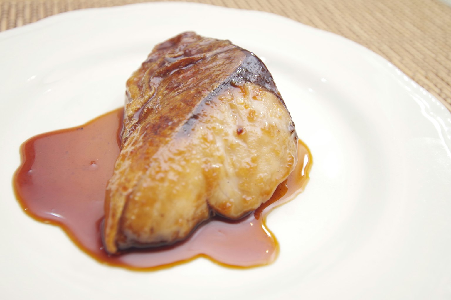 Un filet de poisson délicieux servi avec une sauce sucrée sur une assiette blanche