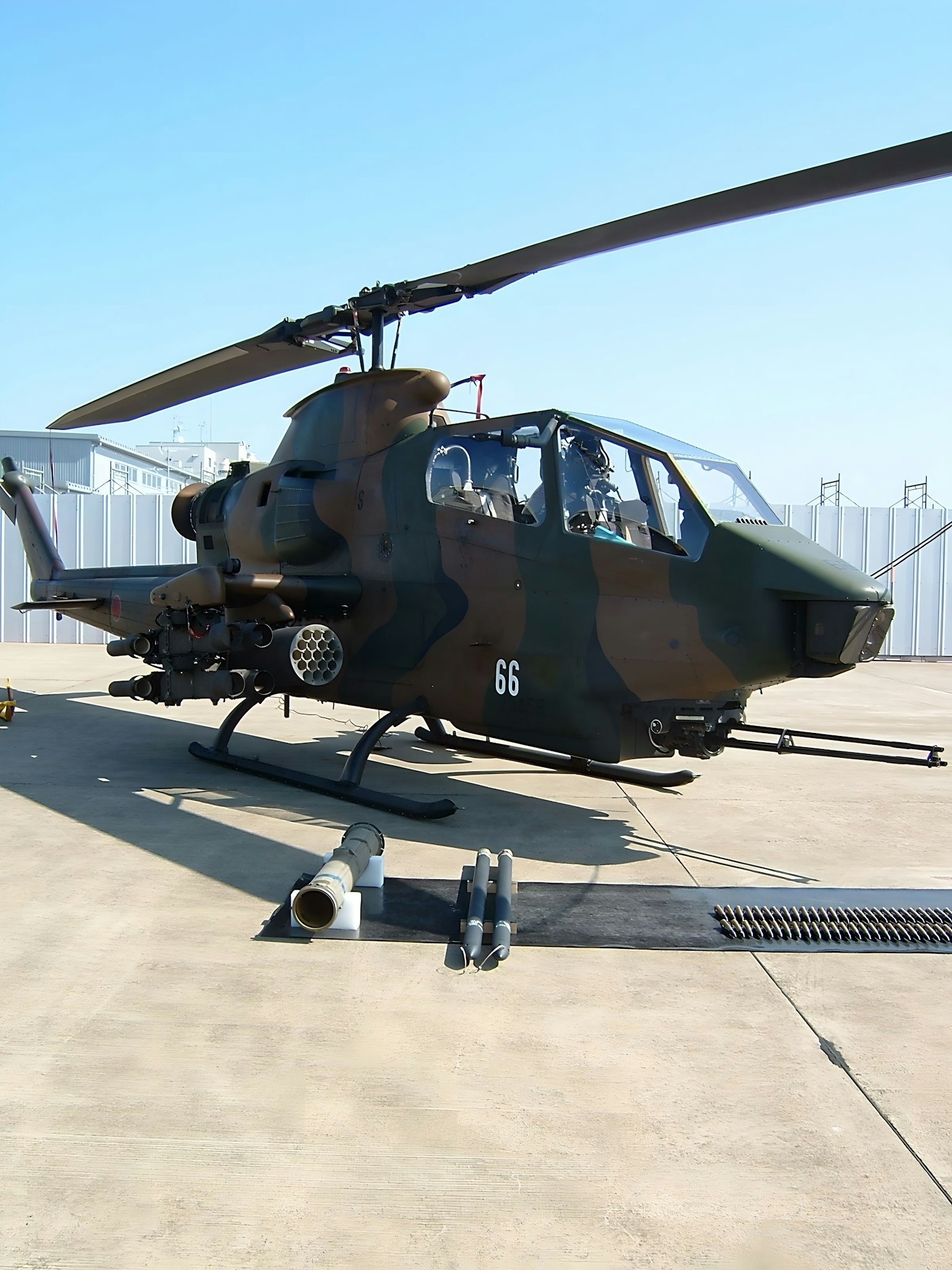 Helikopter militer diparkir di permukaan beton di bawah langit biru yang cerah