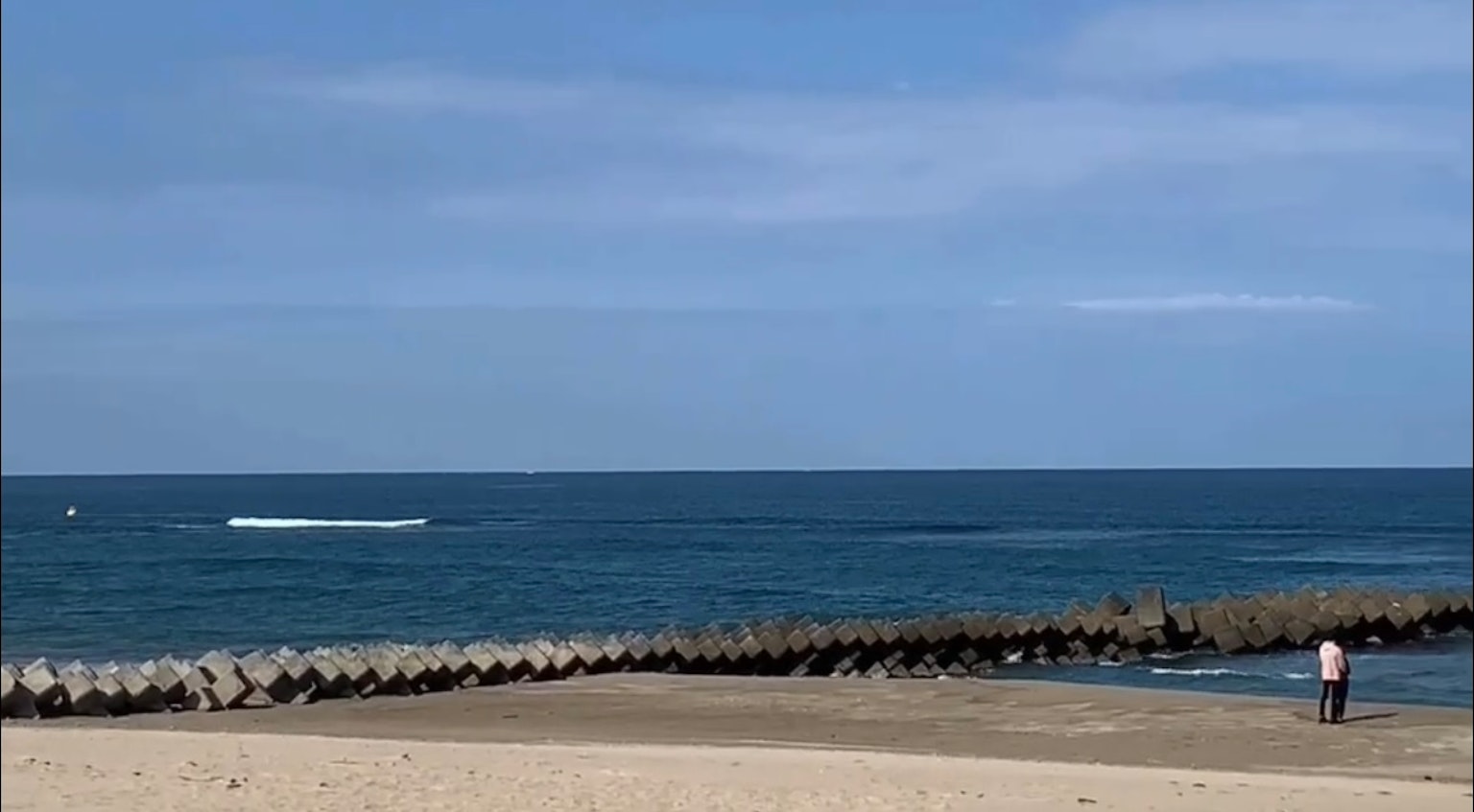 Vue panoramique d'une plage avec un océan bleu et un ciel bleu avec une personne debout