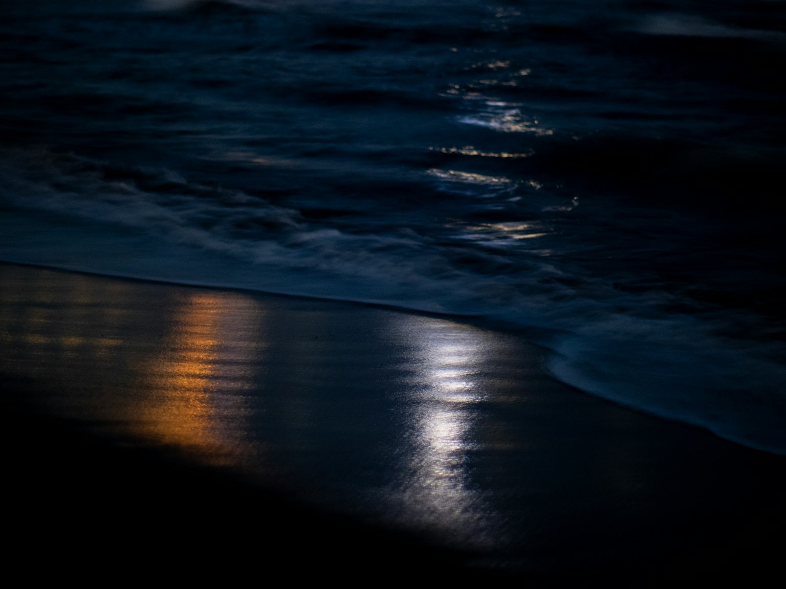 Scène de plage avec des vagues océaniques sombres et une lumière réfléchie