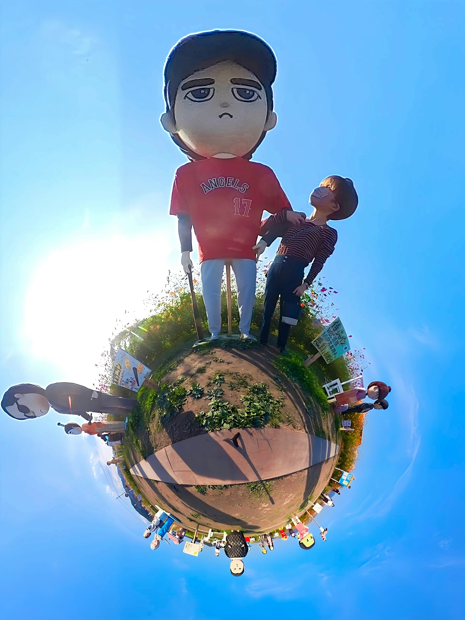 Figurita sobredimensionada y figura más pequeña bajo un cielo azul