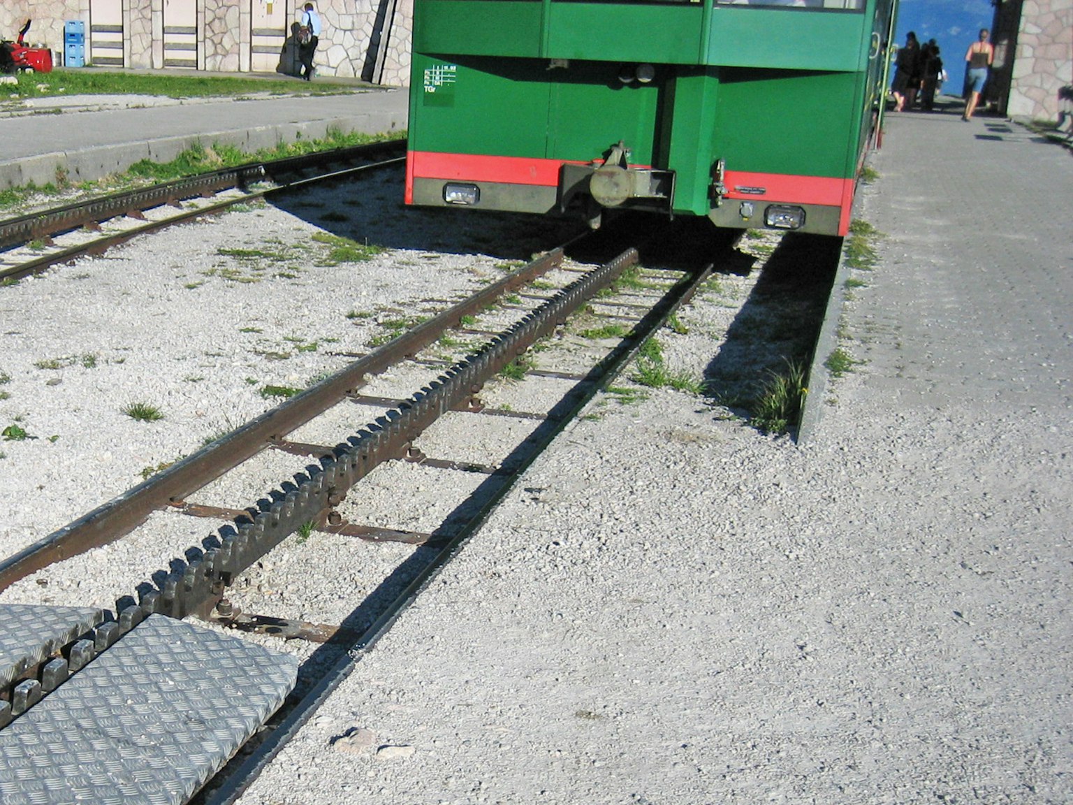 Trolley hijau diparkir di atas rel dengan kerikil di sekelilingnya