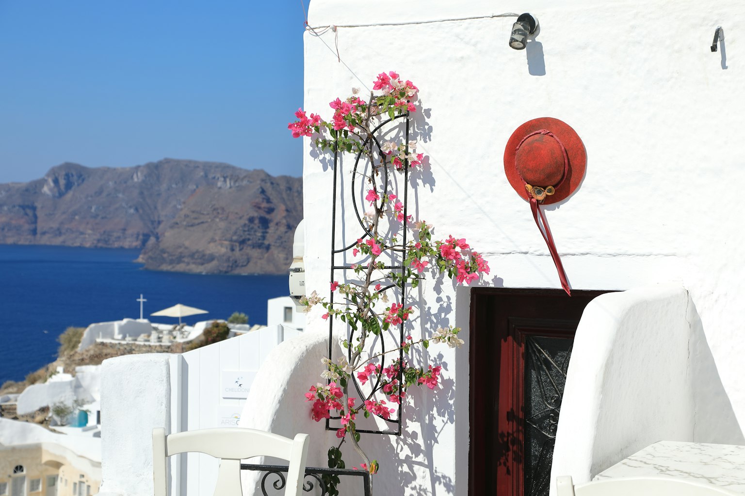 Bella vista di una casa bianca adornata con fiori rosa e mare blu