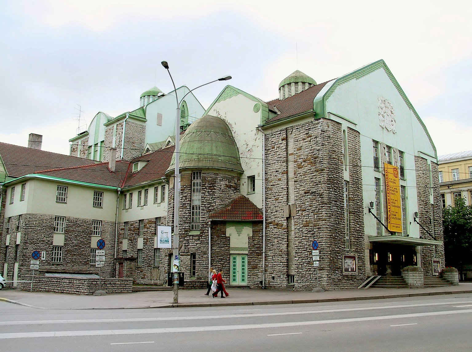 Exterior of a stone building with green roofs and an art museum banner
