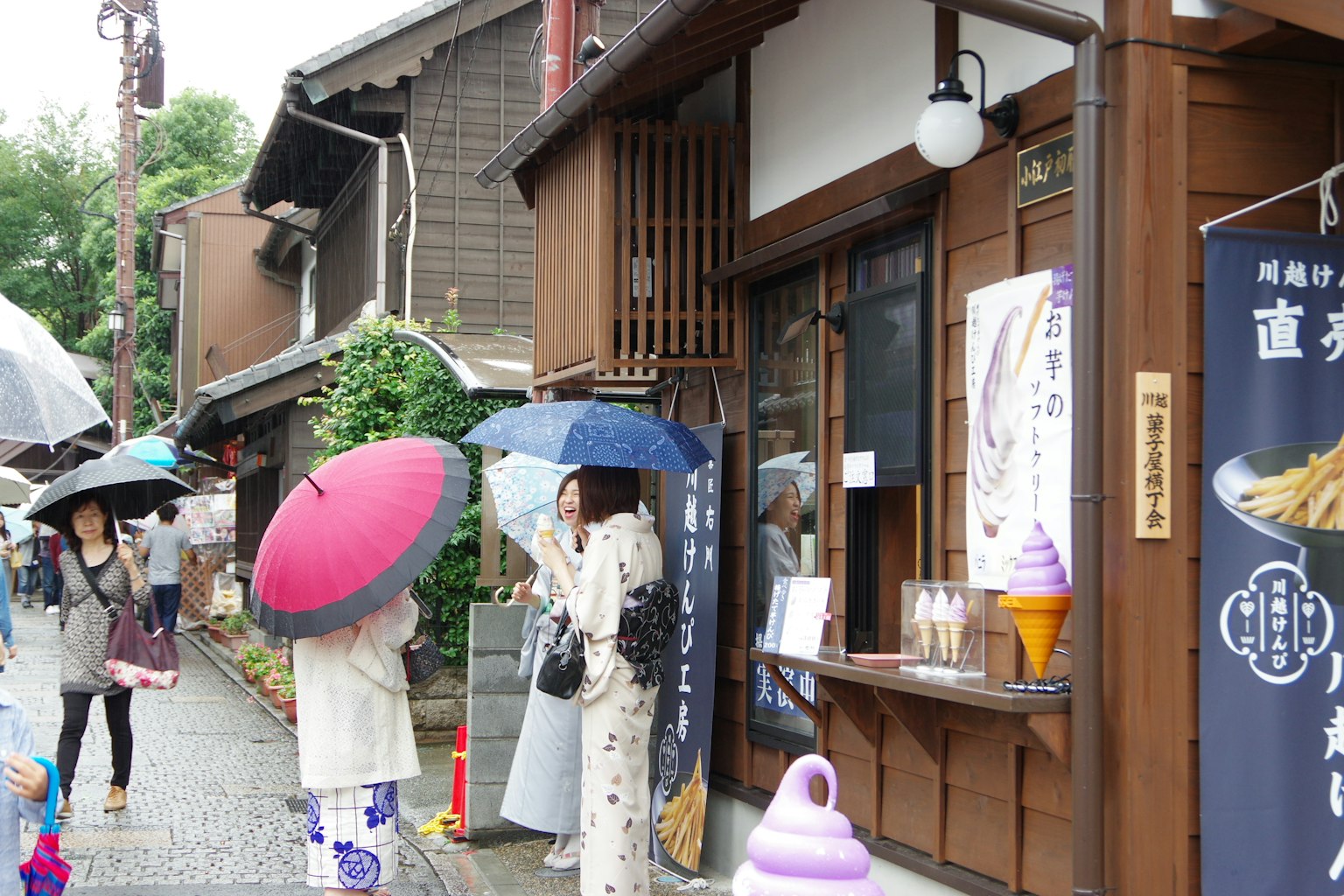 人們在雨中站在傳統建築前，手持雨傘