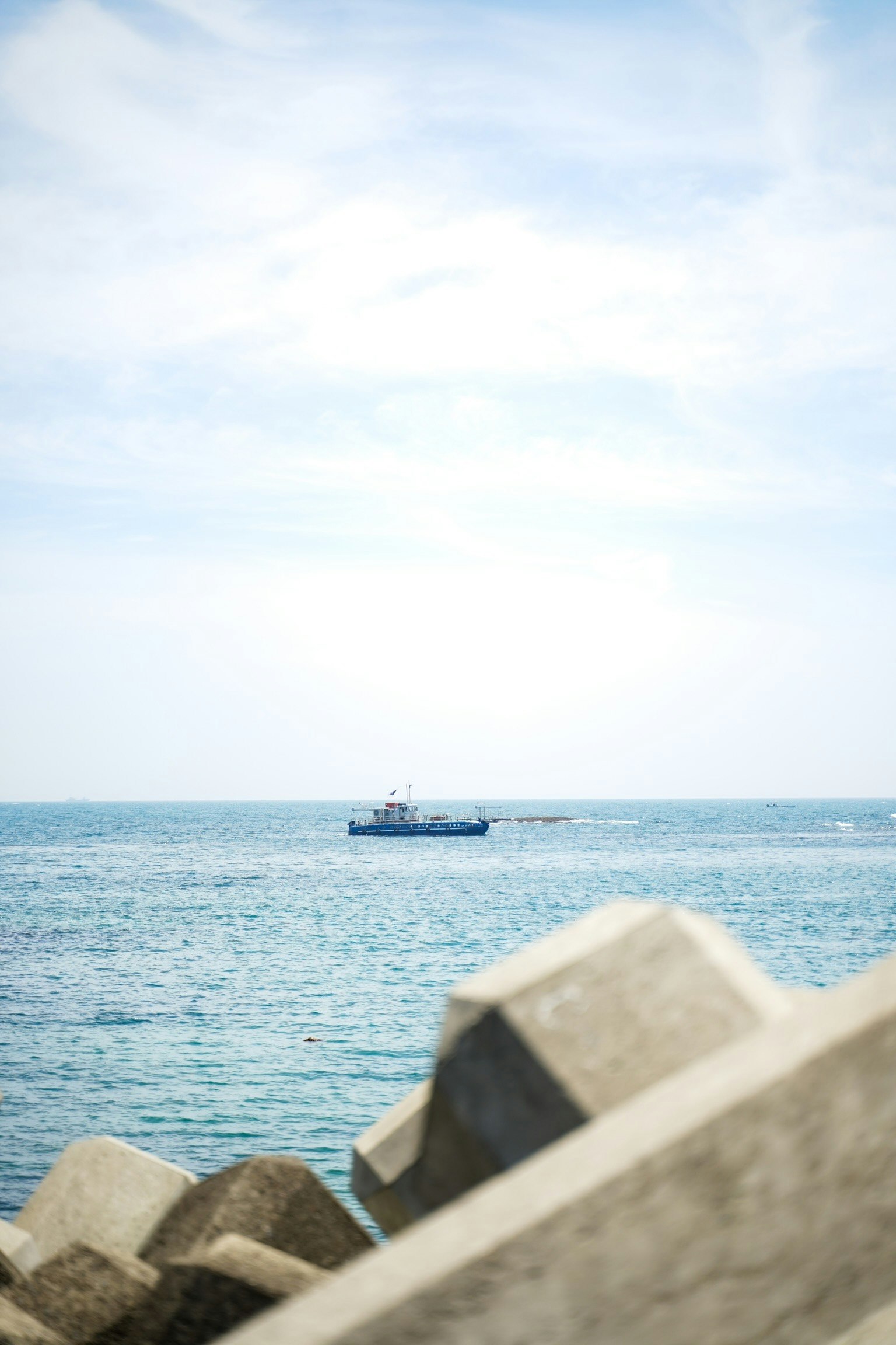 Vista panoramica del mare blu con una barca in lontananza e rocce in primo piano