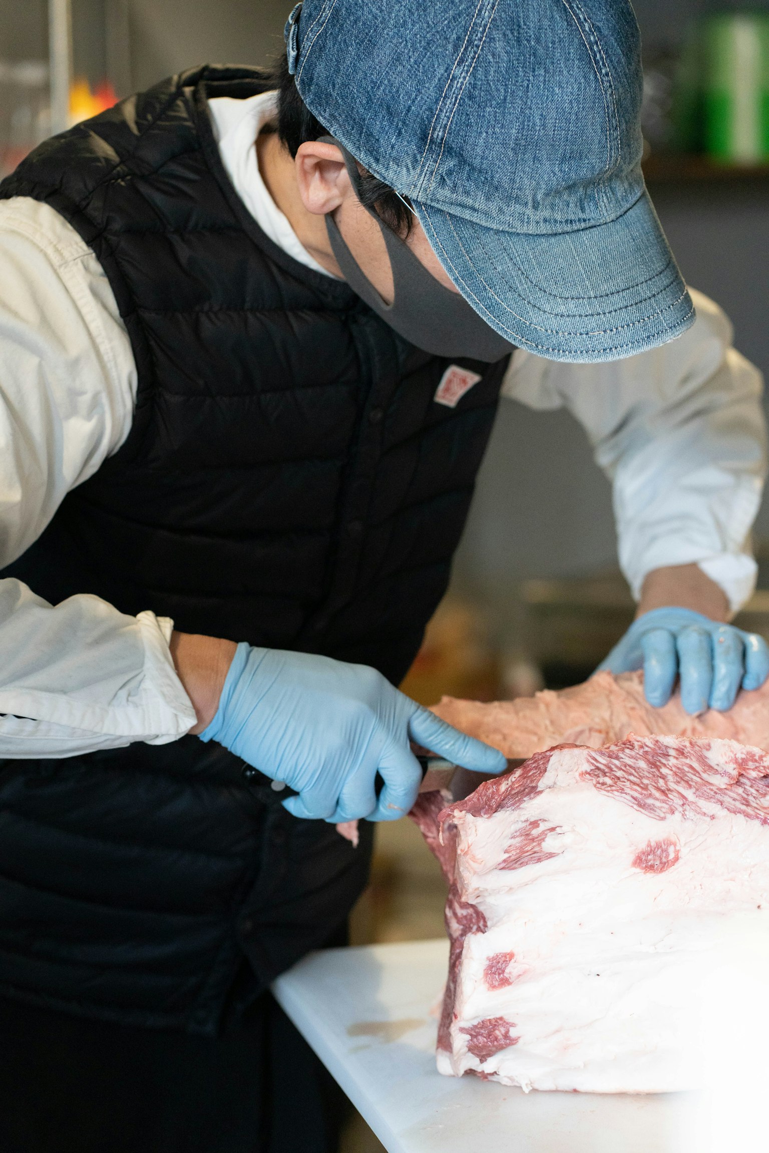 Uomo che taglia carne indossando abbigliamento da chef e guanti