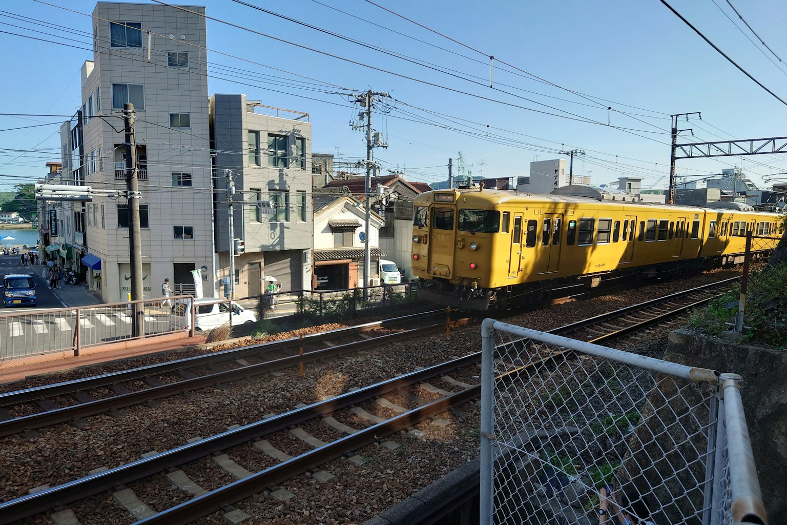 A yellow train running along tracks in an urban setting