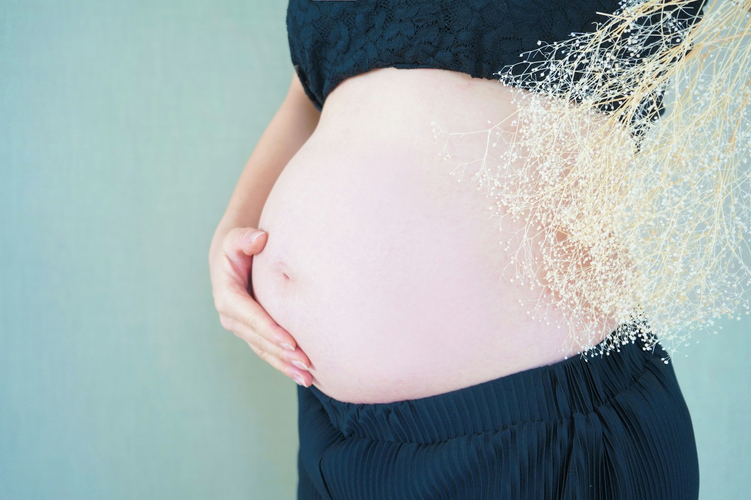 Pregnant woman cradling her belly with soft fibers dispersing around