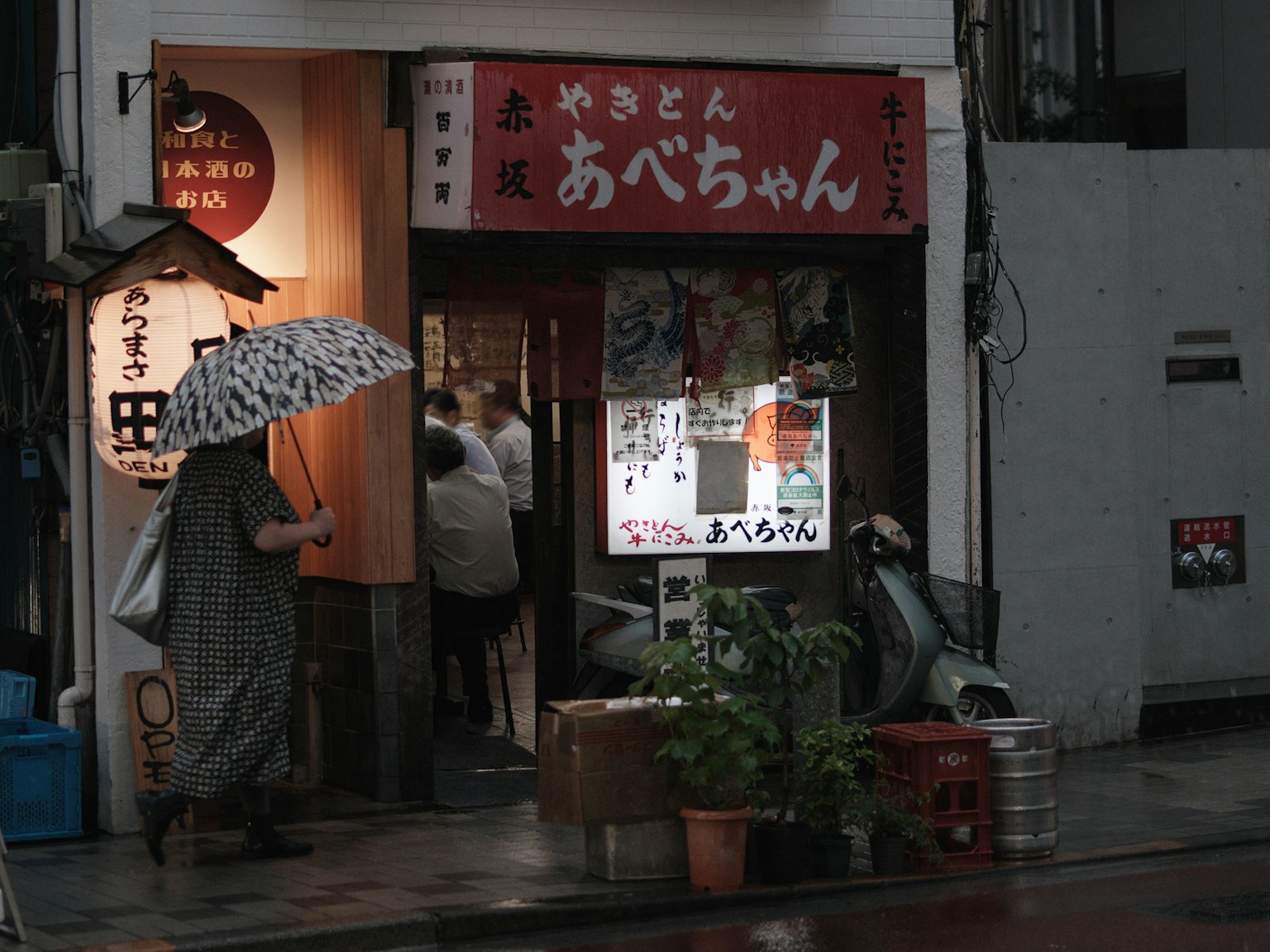 雨中的小餐館外觀 人手持雨傘 紅色招牌上有日文字符