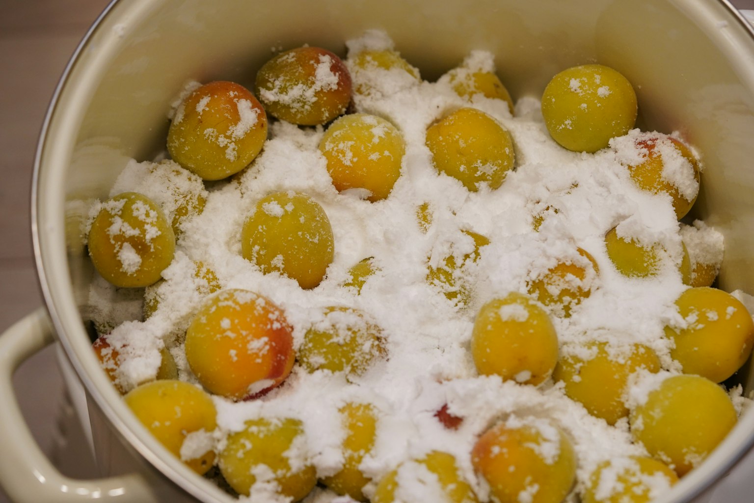 Pentola piena di prugne gialle coperte di zucchero