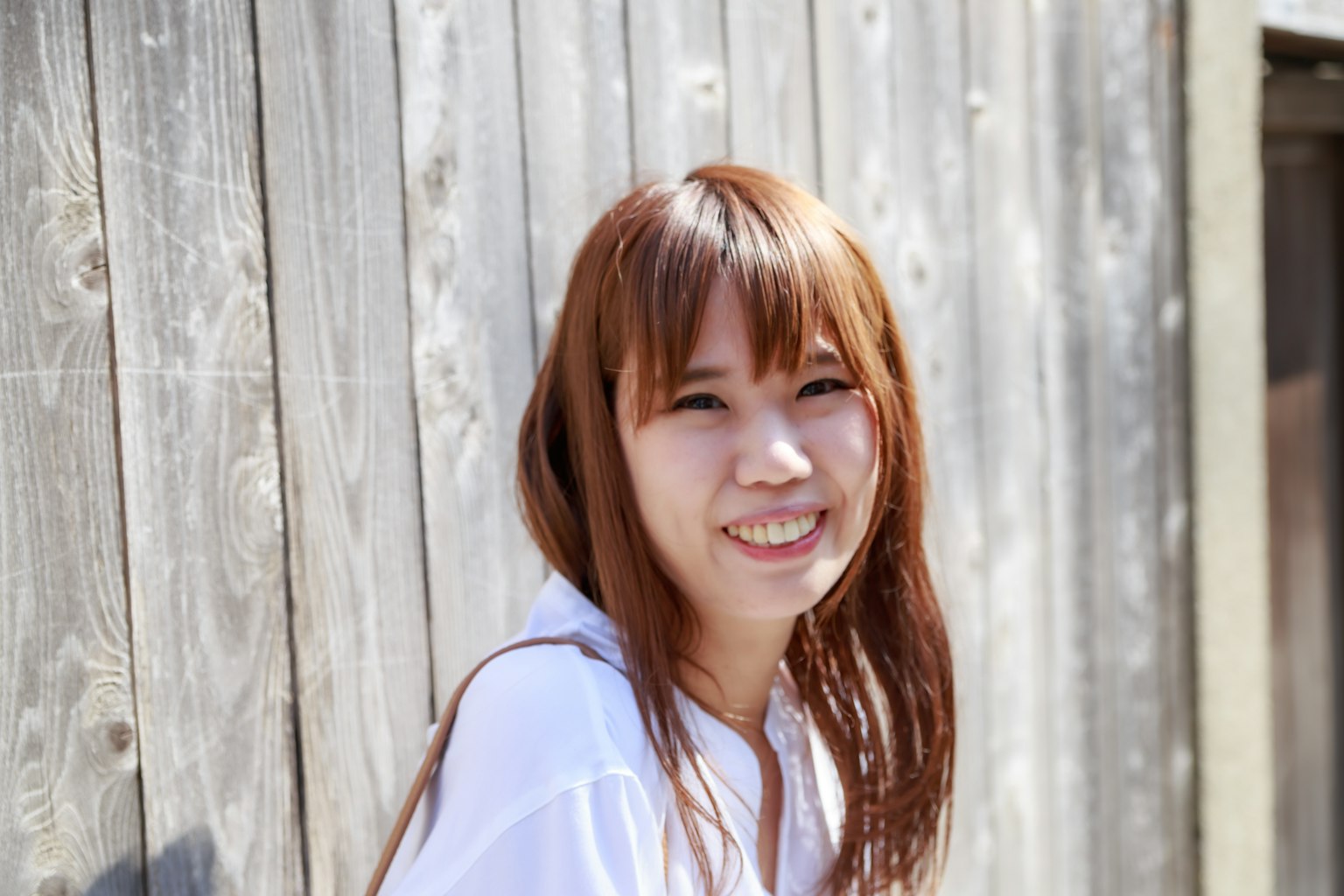 หญิงสาวยิ้มแย้มอยู่หน้าผนังไม้