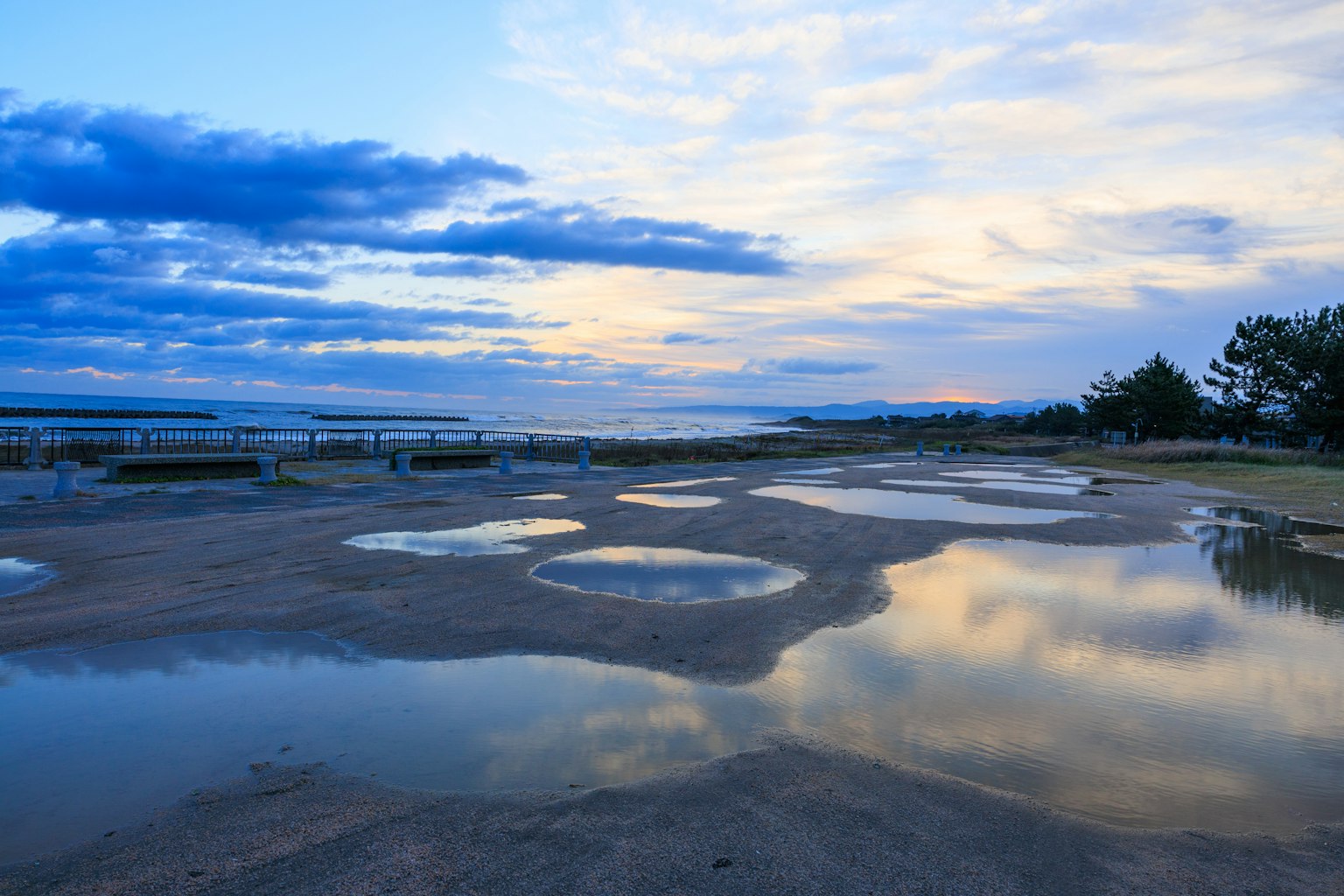 Coastal landscape with puddles reflecting blue sky and clouds