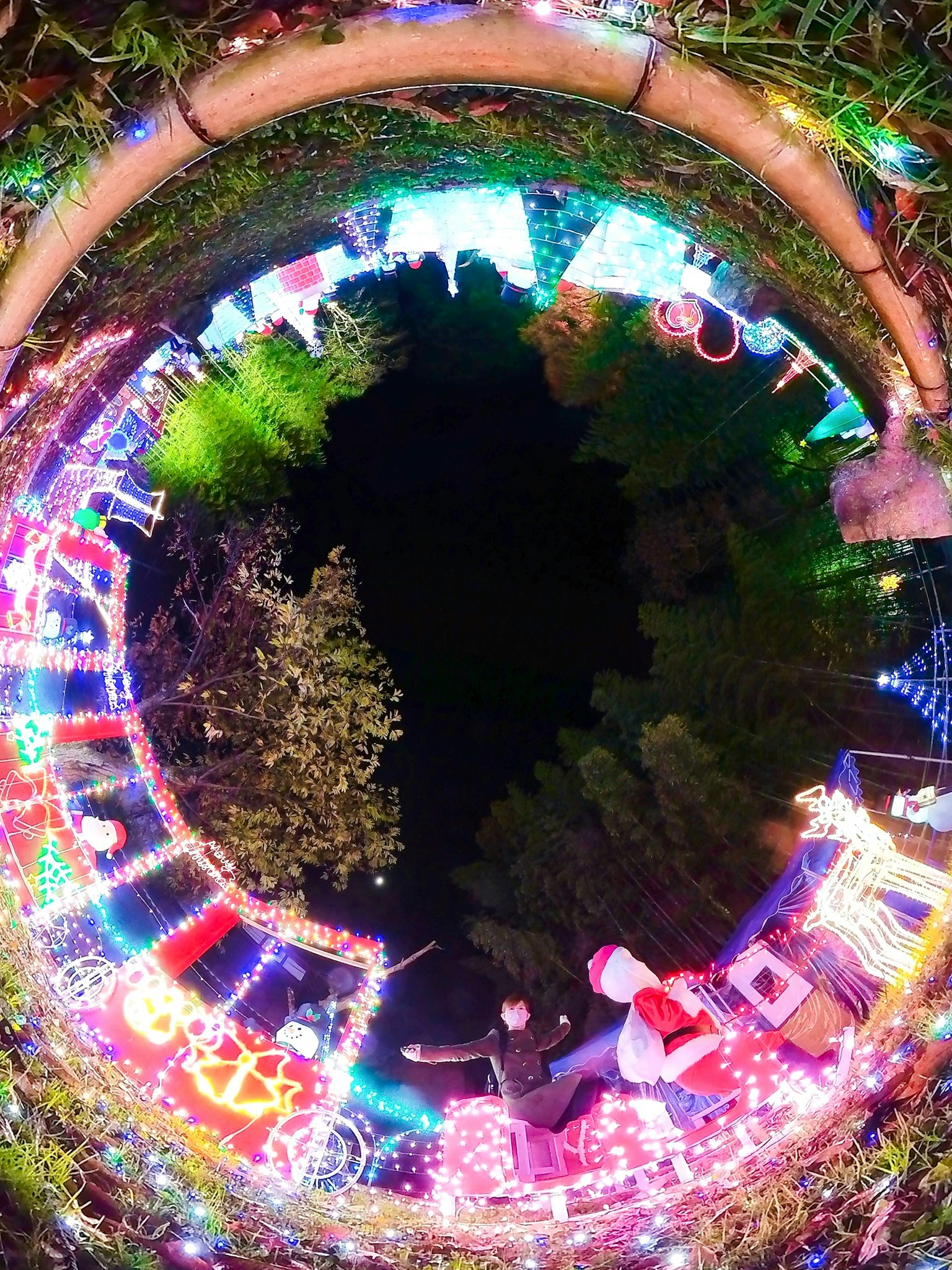 Vista circular de un parque adornado con luces de Navidad coloridas creando una atmósfera mágica nocturna