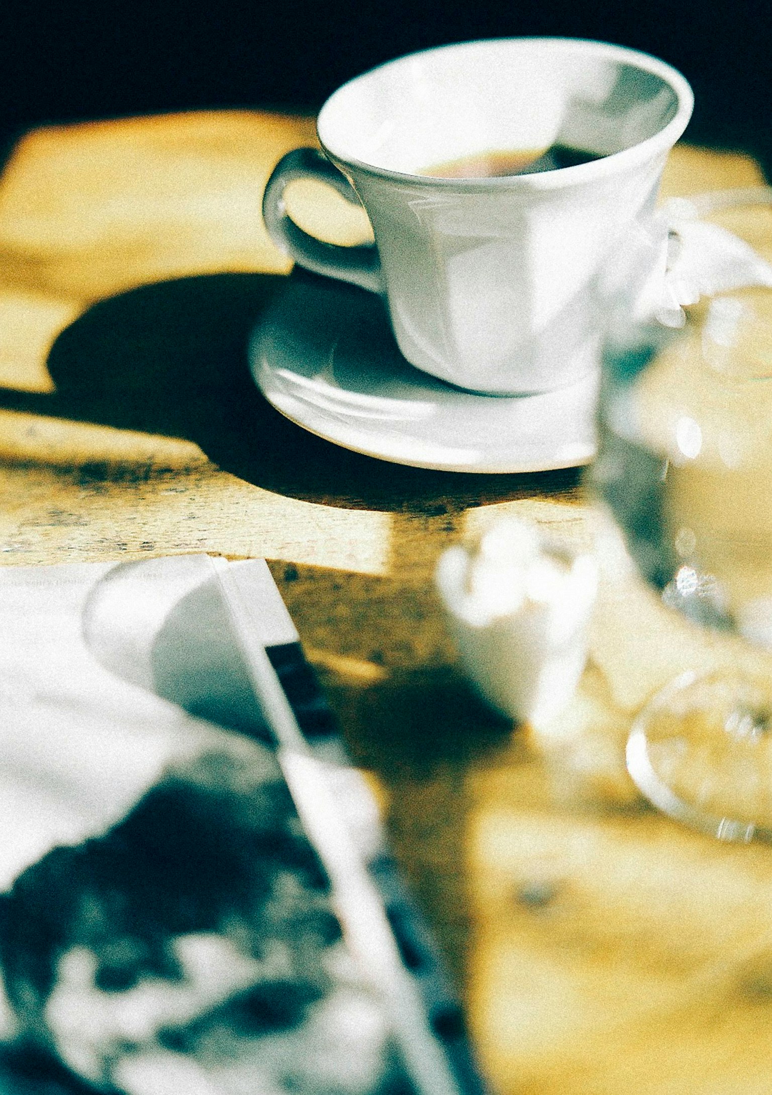 Une tasse de café blanche sur une soucoupe avec du café et un verre d'eau sur une table en bois