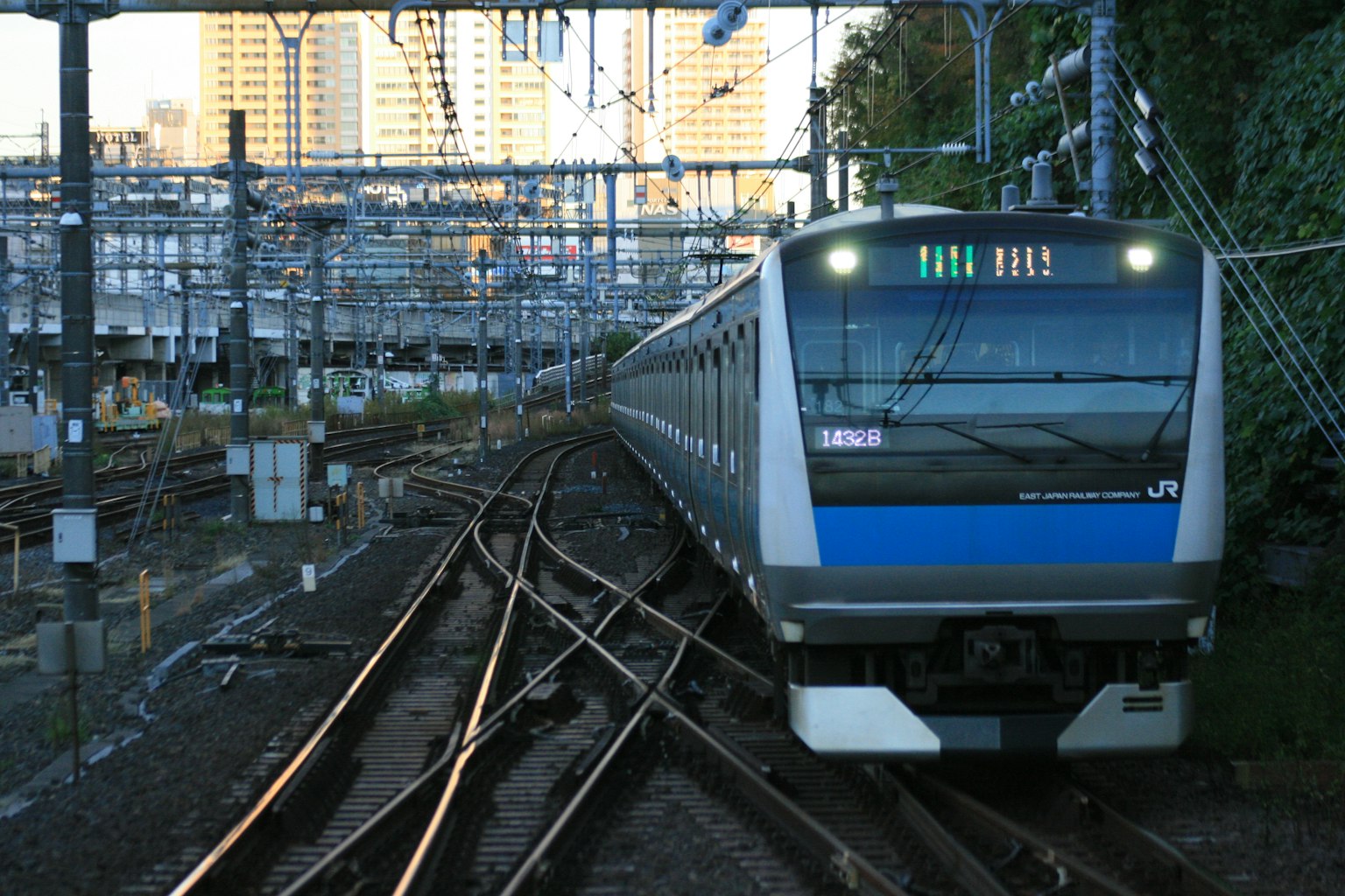 รถไฟสีน้ำเงินที่วิ่งผ่านรางหลายรางในสภาพแวดล้อมในเมือง