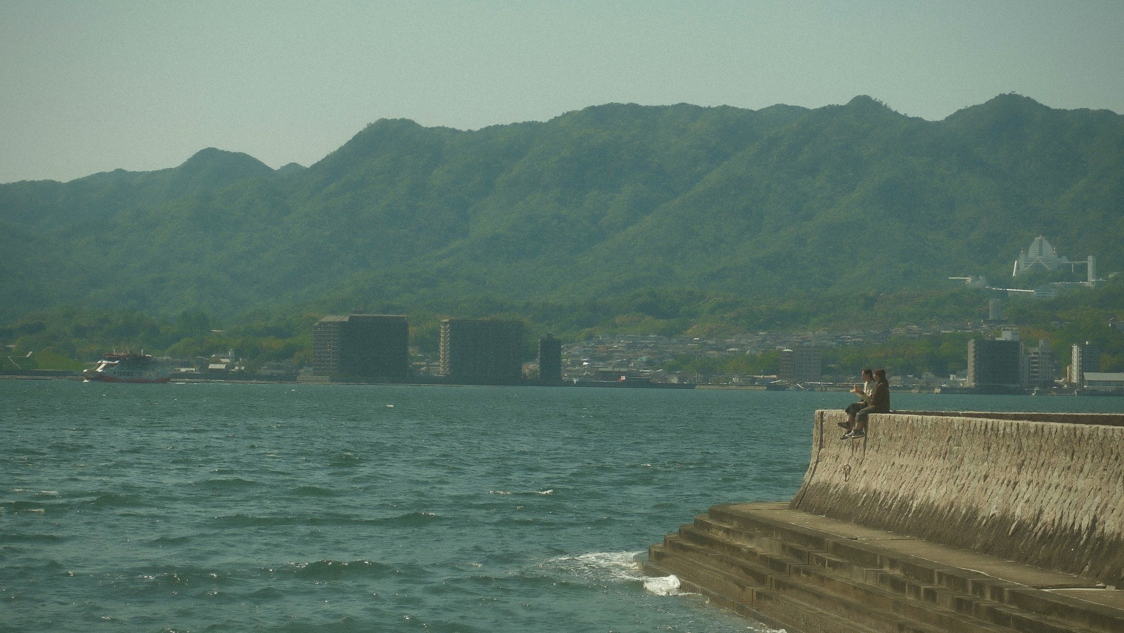 海沿いの防波堤と山並みが広がる風景