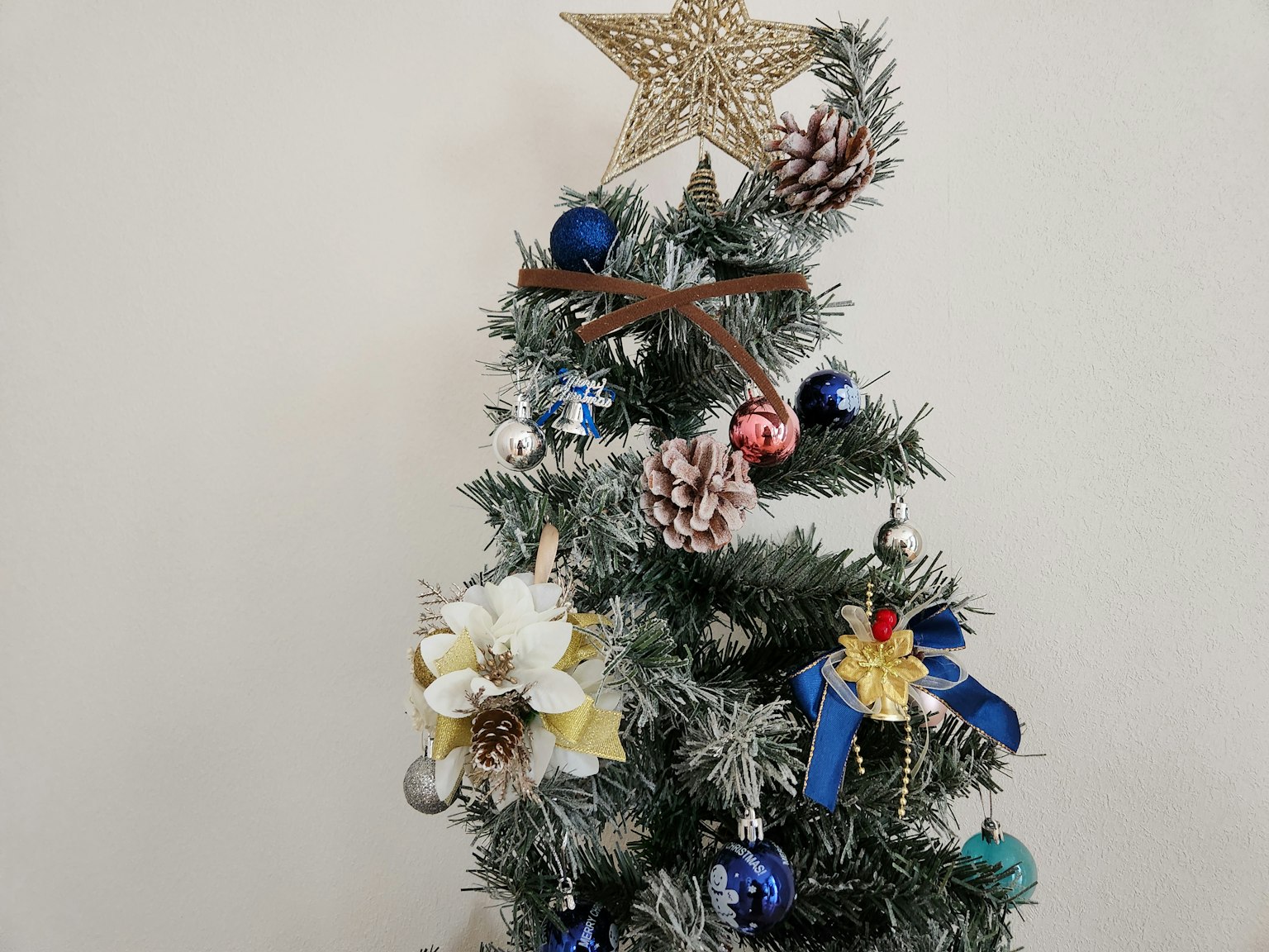 Sapin de Noël décoré d'ornements bleus et blancs surmonté d'une étoile