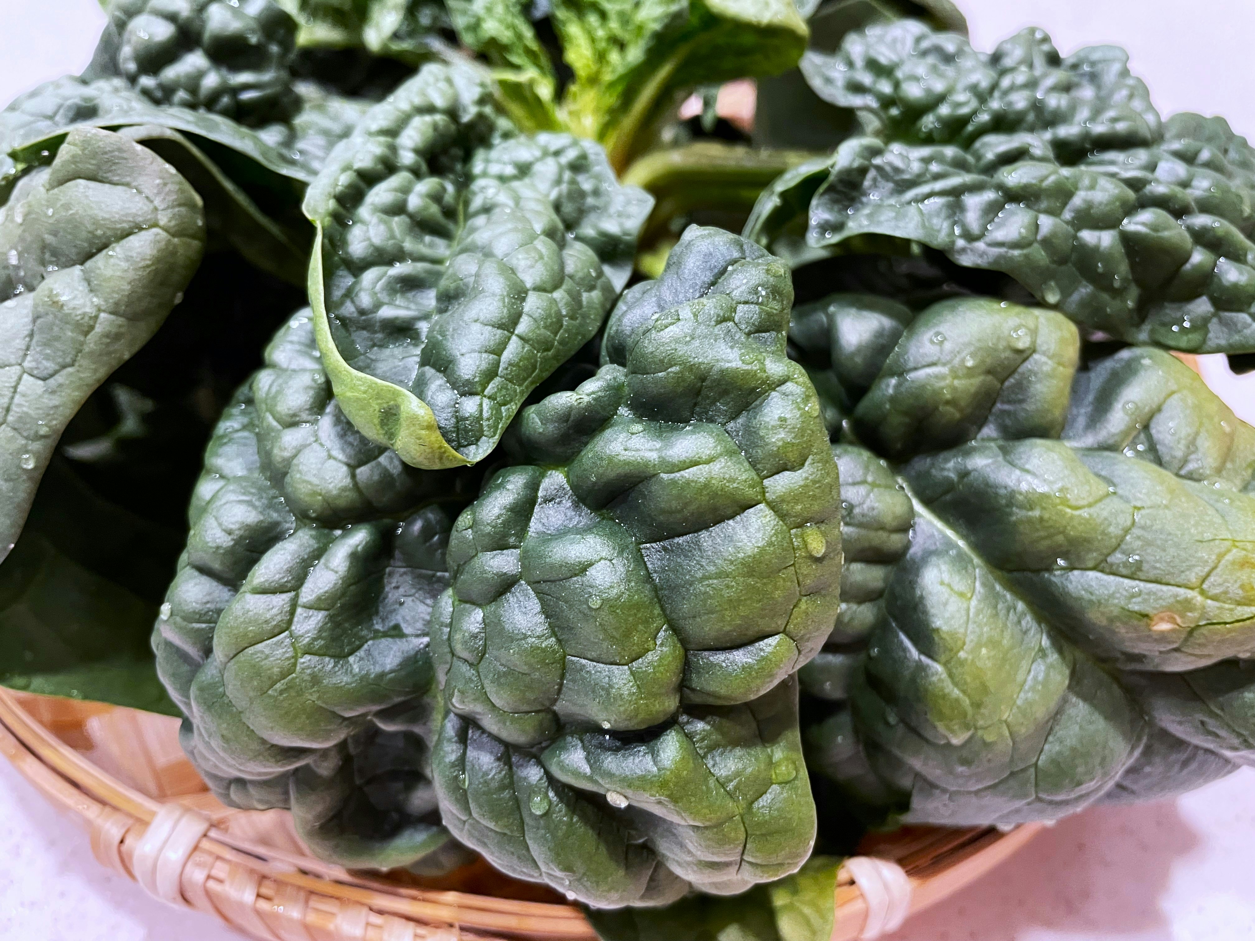 Pile of crinkled spinach leaves with deep ridges and texture