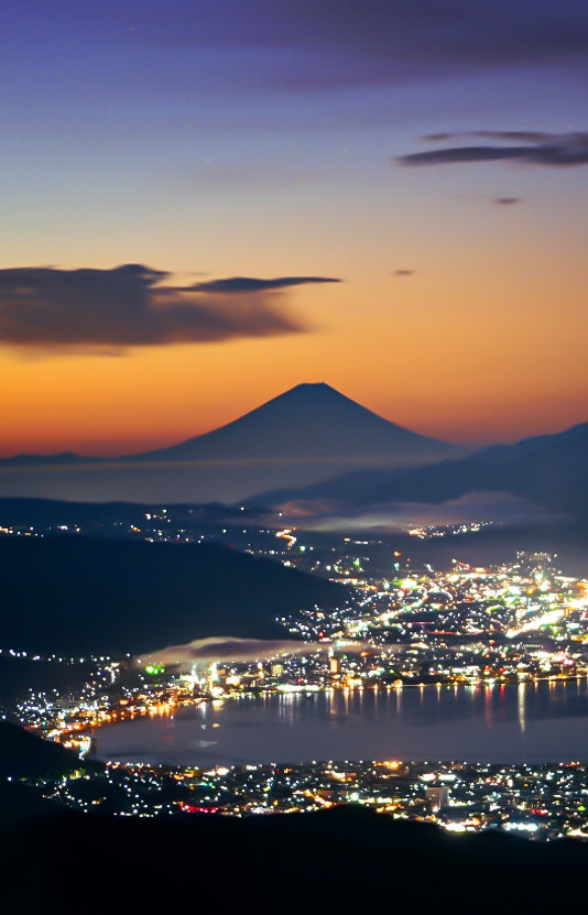 夜景の街並みとそびえる山のシルエット