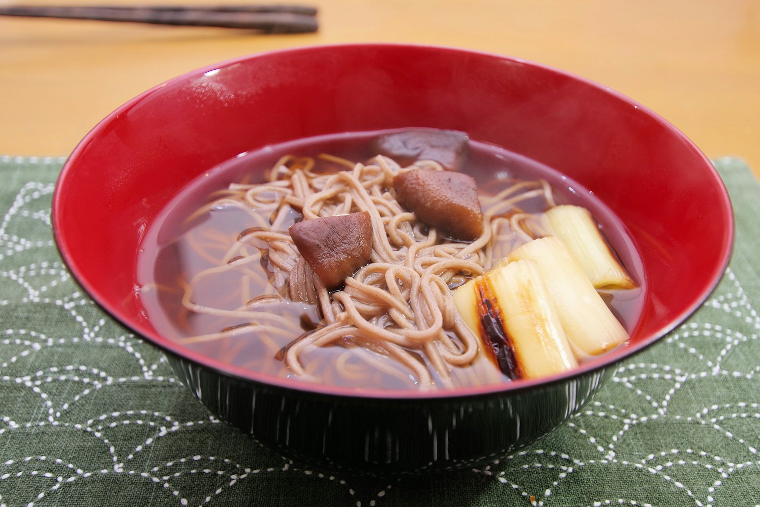 Nouilles soba dans un bol rouge avec de la pâte de haricots rouges sucrée et des morceaux de radis blanc