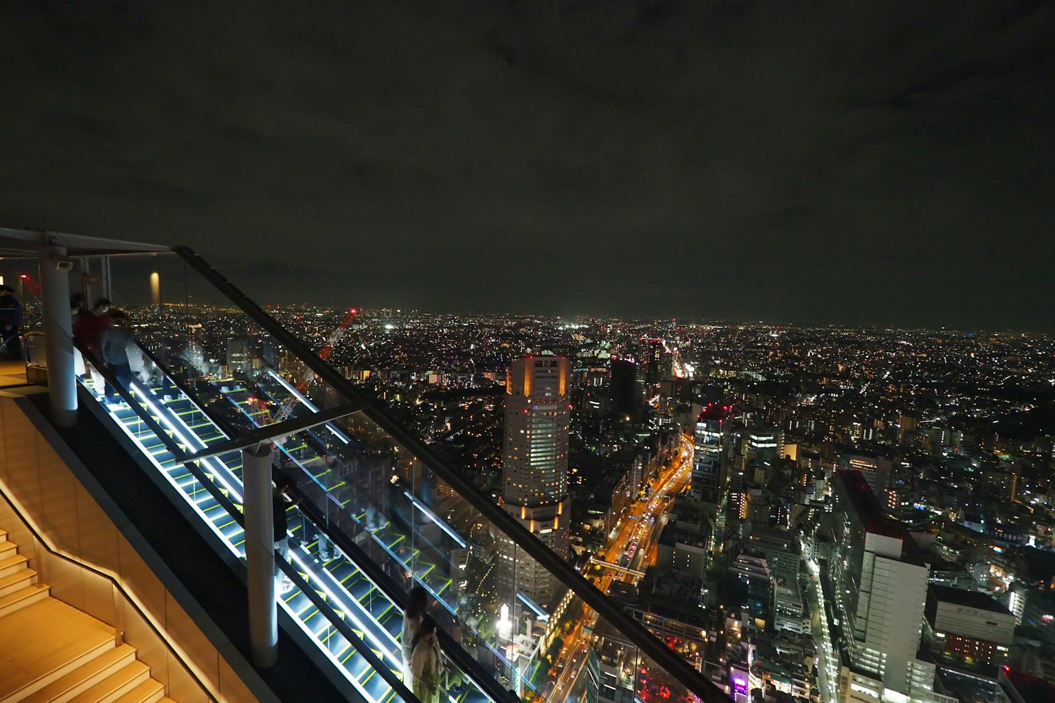 View of Tokyo at night from a high-rise building with people enjoying the scenery