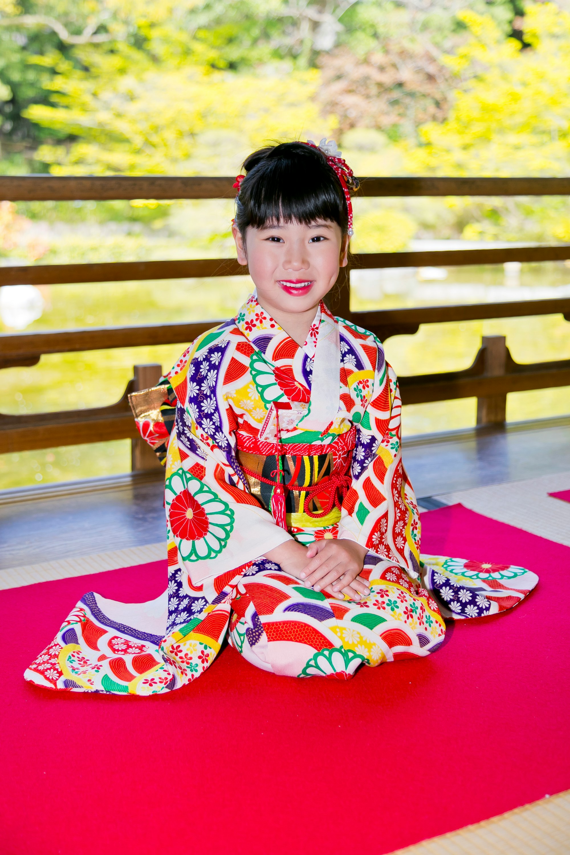 庭園を背景に座る子どもの晴れ着姿
