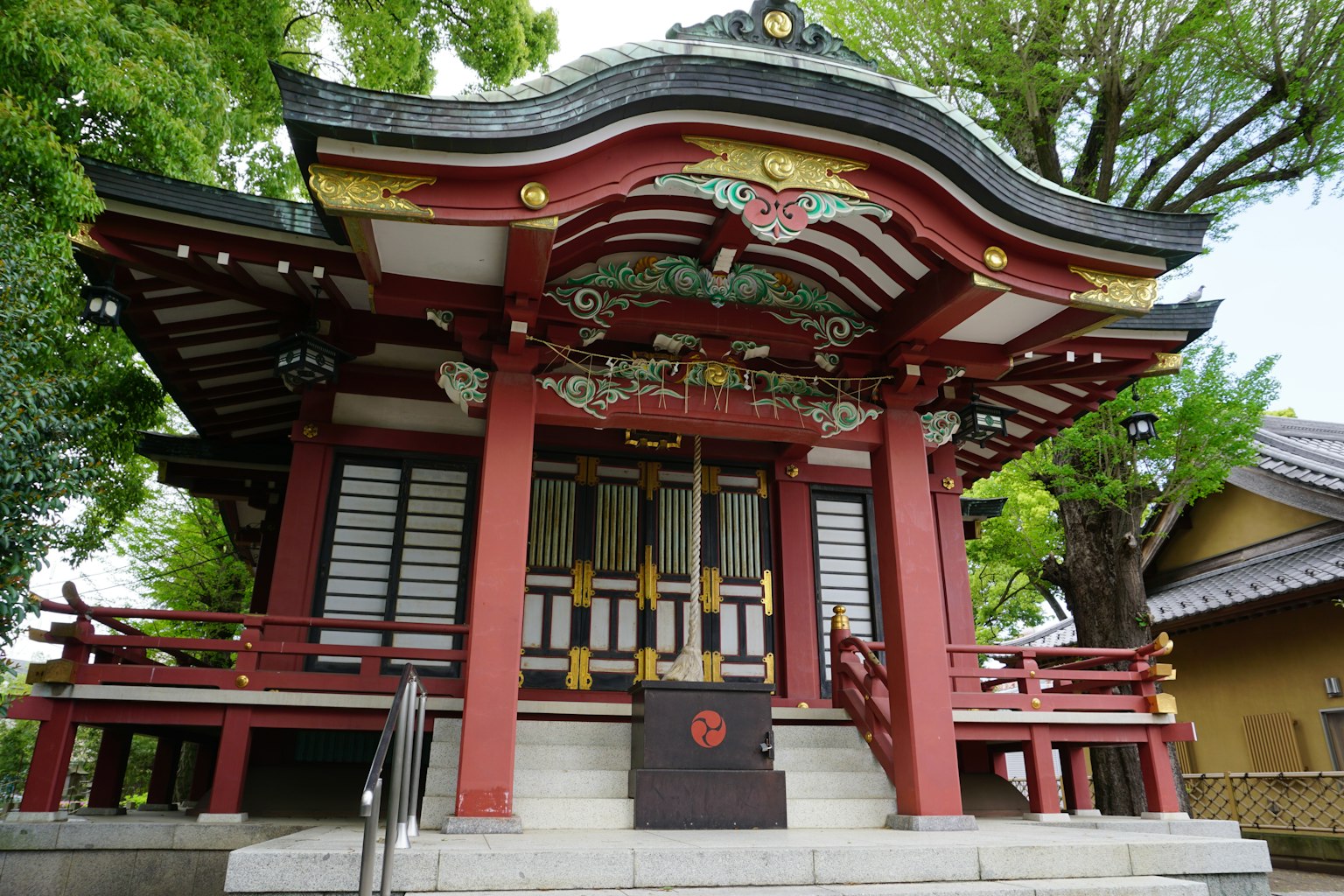 一座紅色屋頂和複雜裝飾的神社建築 被郁郁蔥蔥的綠色樹木環繞