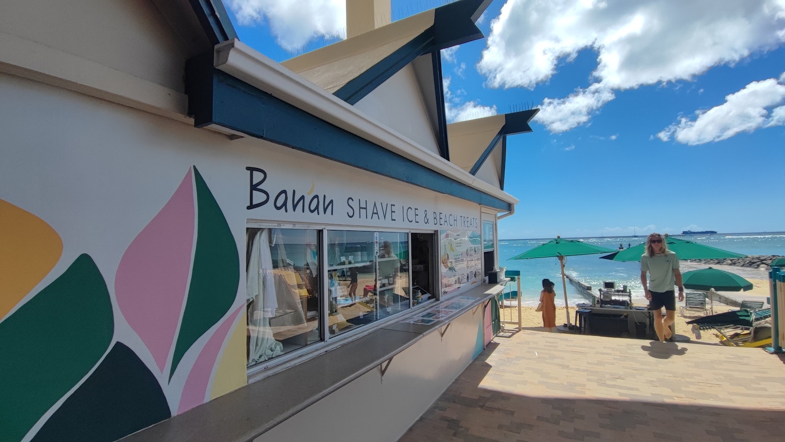 Extérieur d'un stand de collations à la banane près de la plage avec un ciel bleu et l'océan en arrière-plan
