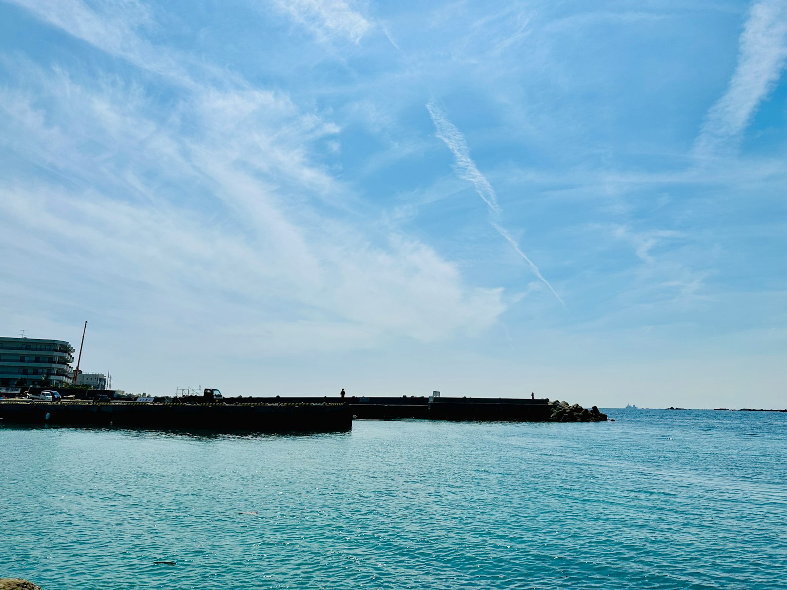 Scenic view of calm turquoise water and bright sky with a pier
