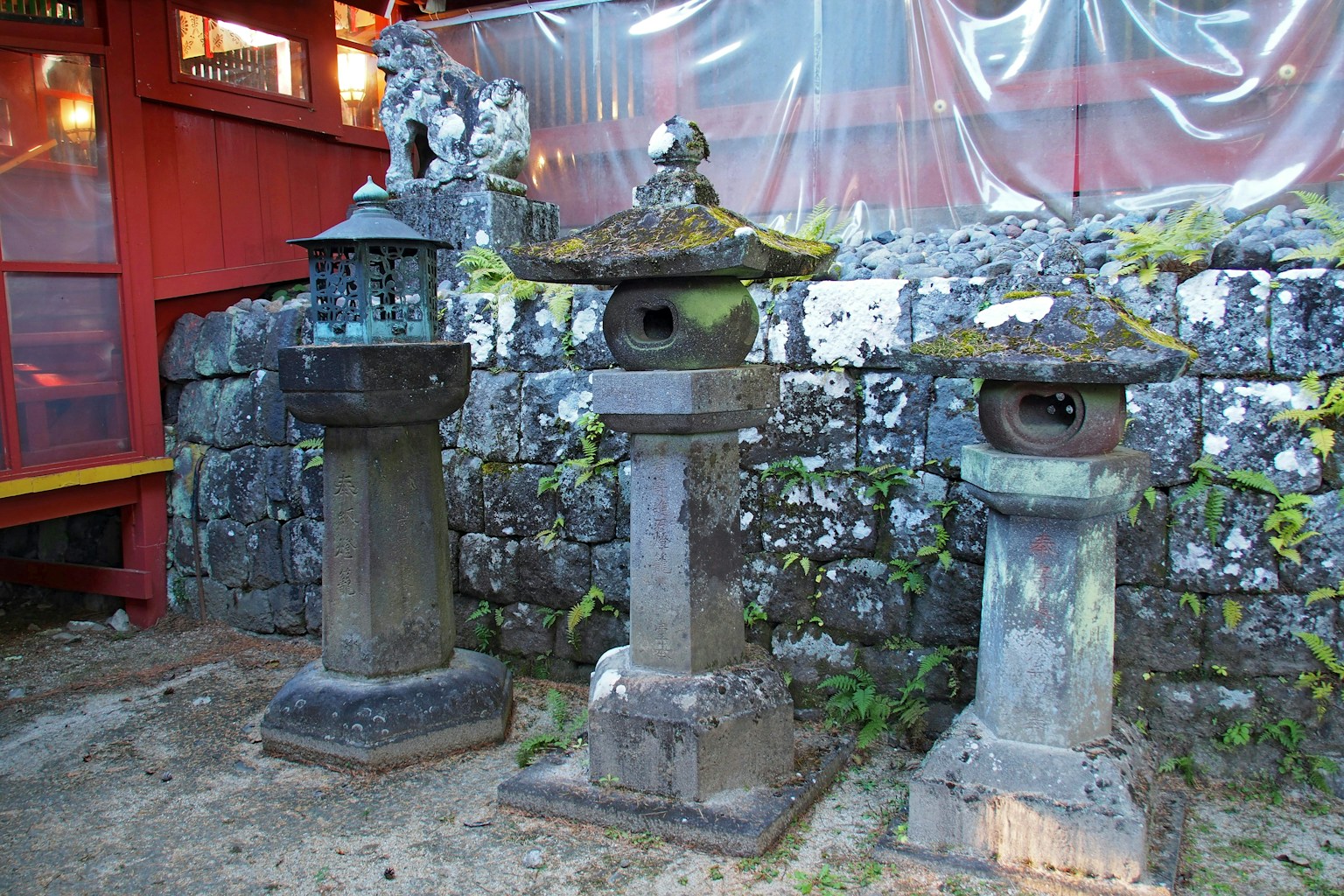 三盞傳統石燈籠在花園中苔蘚覆蓋的燈籠和石牆背景