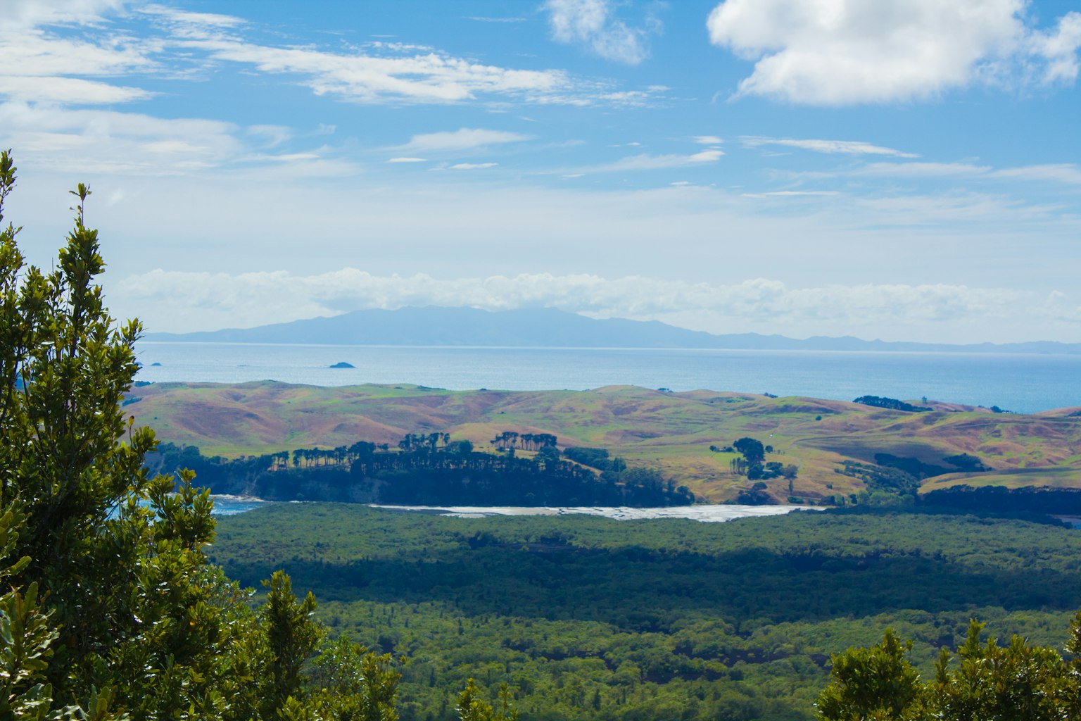 Panoramablick auf grüne Hügel und einen See unter blauem Himmel