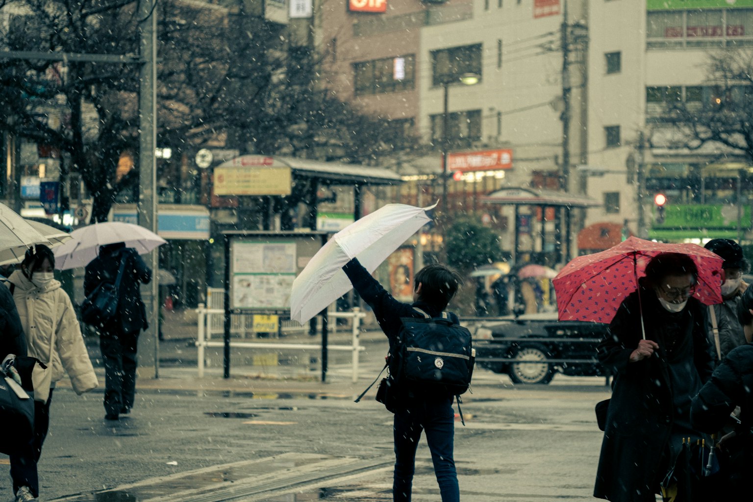 Eine Stadtszene mit Menschen, die im Regen mit Regenschirmen gehen