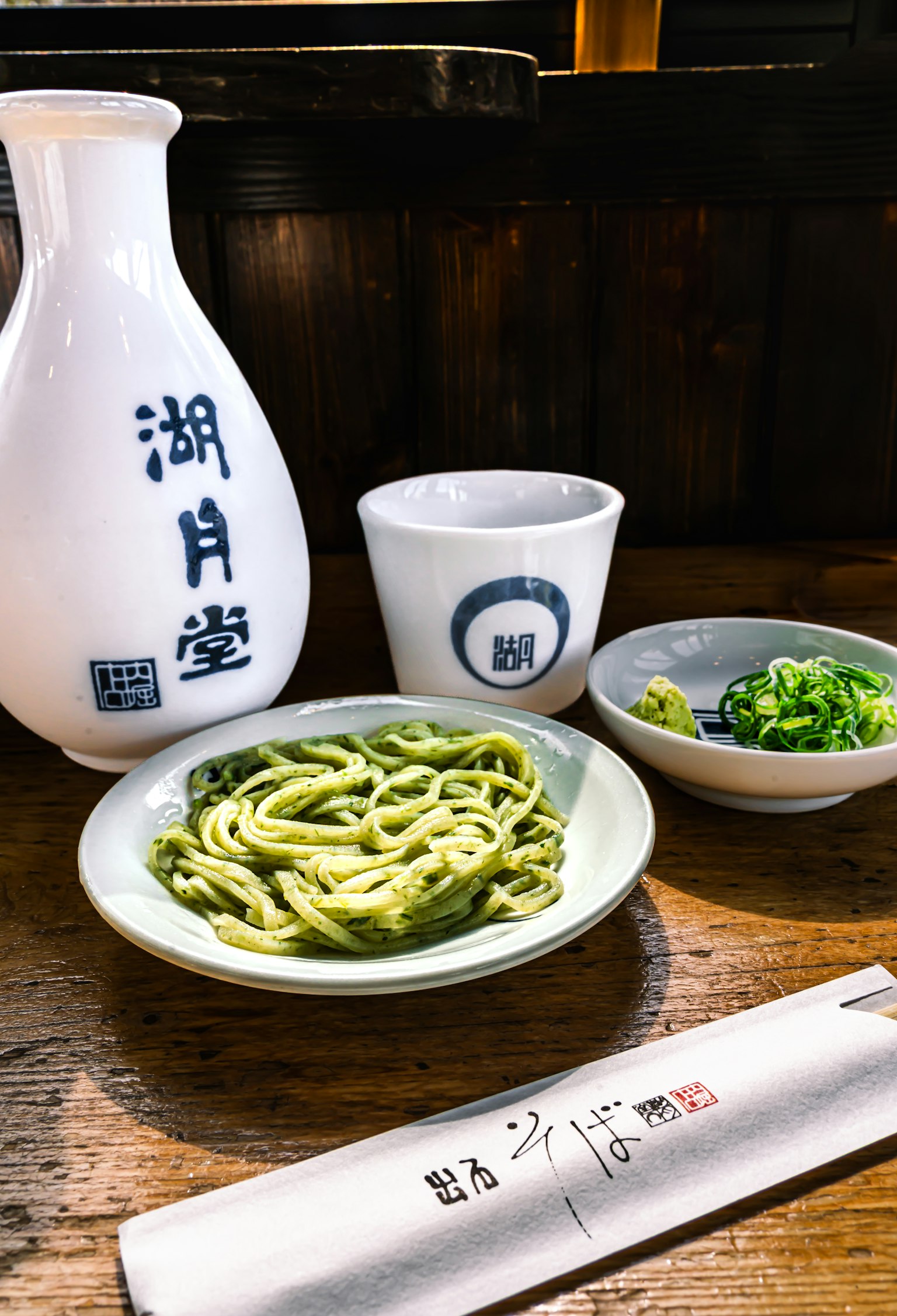 Comida japonesa tradicional con fideos verdes y condimentos botella de sake y platos pequeños