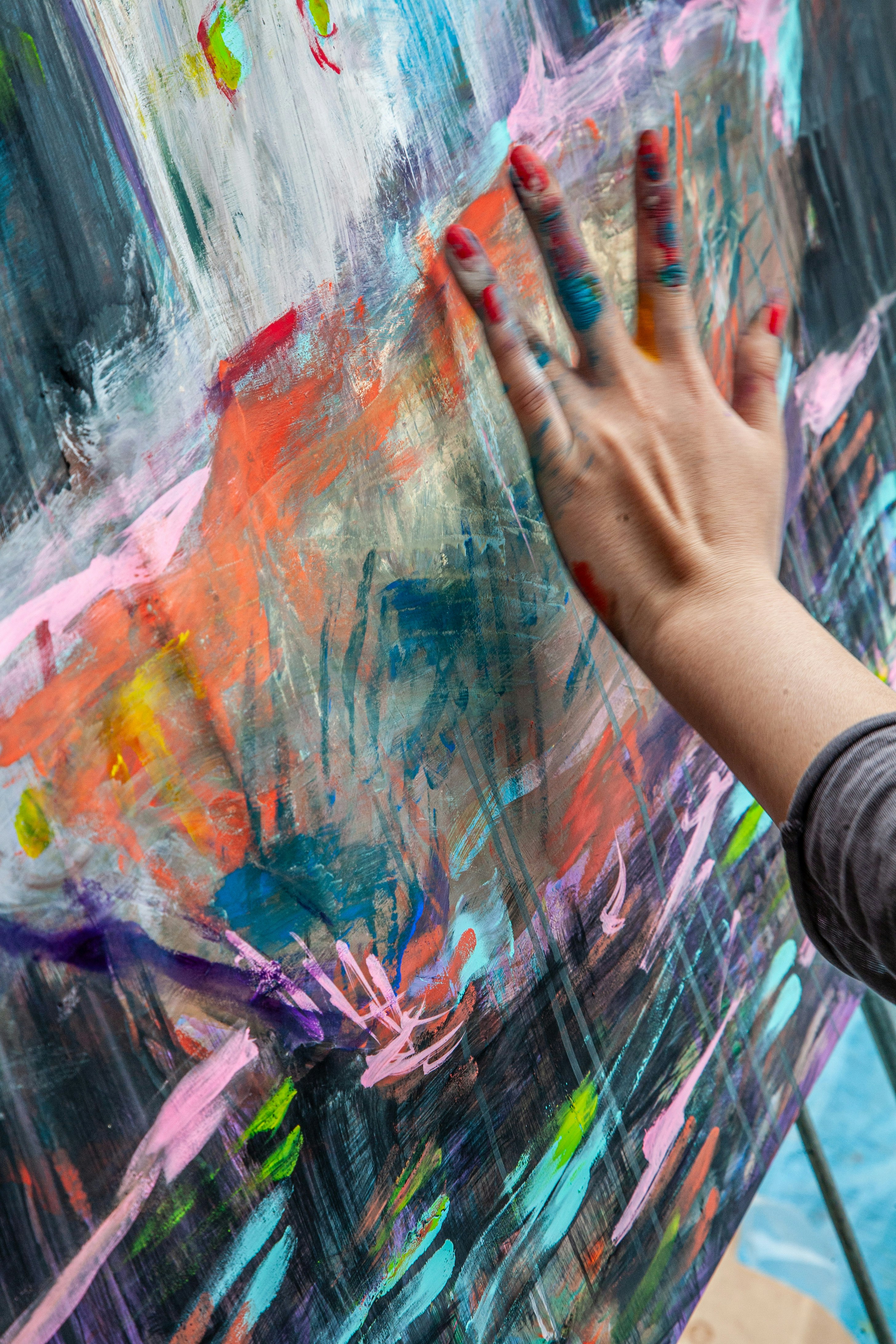 Hand beim Bemalen von farbenfroher Street-Art an einer Wand