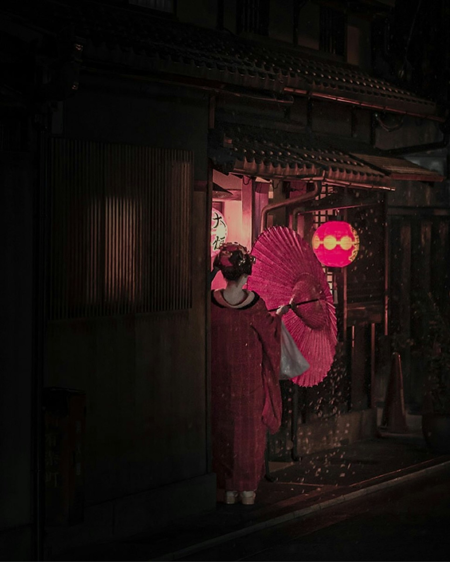 穿着红色和服的女人手持伞站在明亮的入口处
