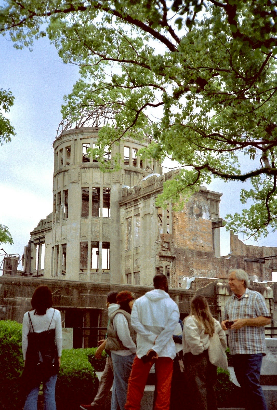 木々の下で見学する人々と遺跡風の建物