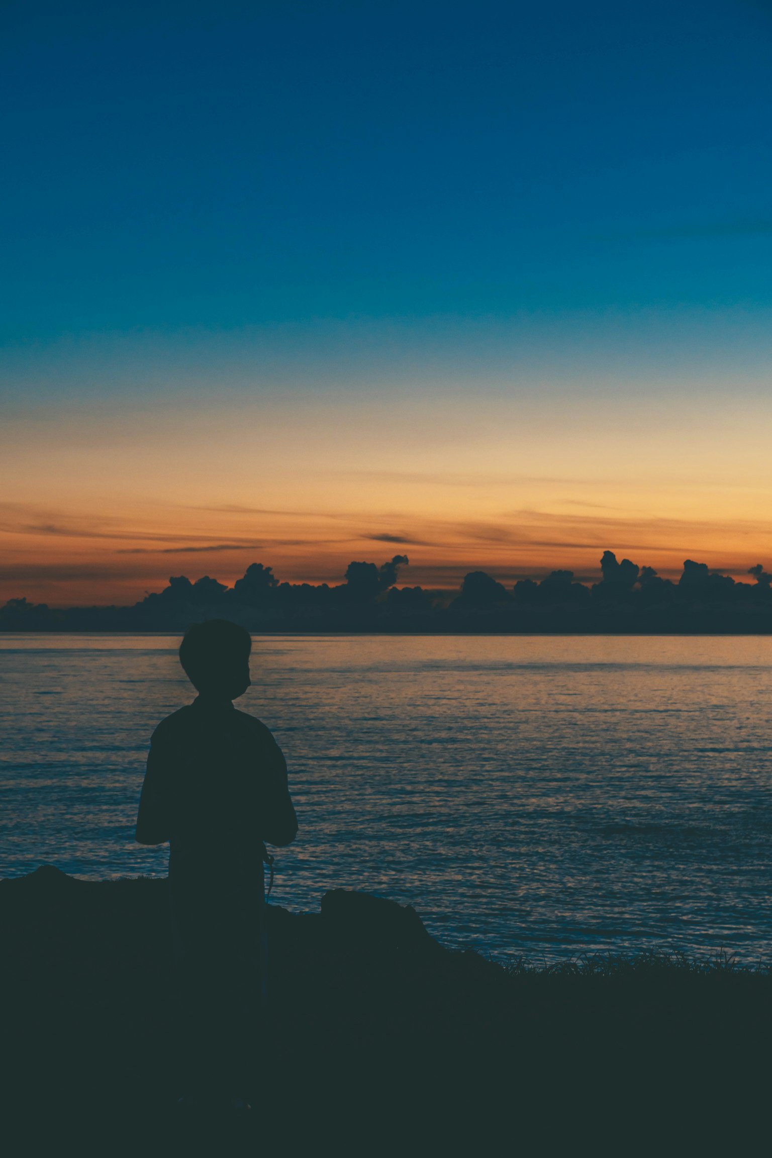 夕阳背景下凝视海洋的人物轮廓