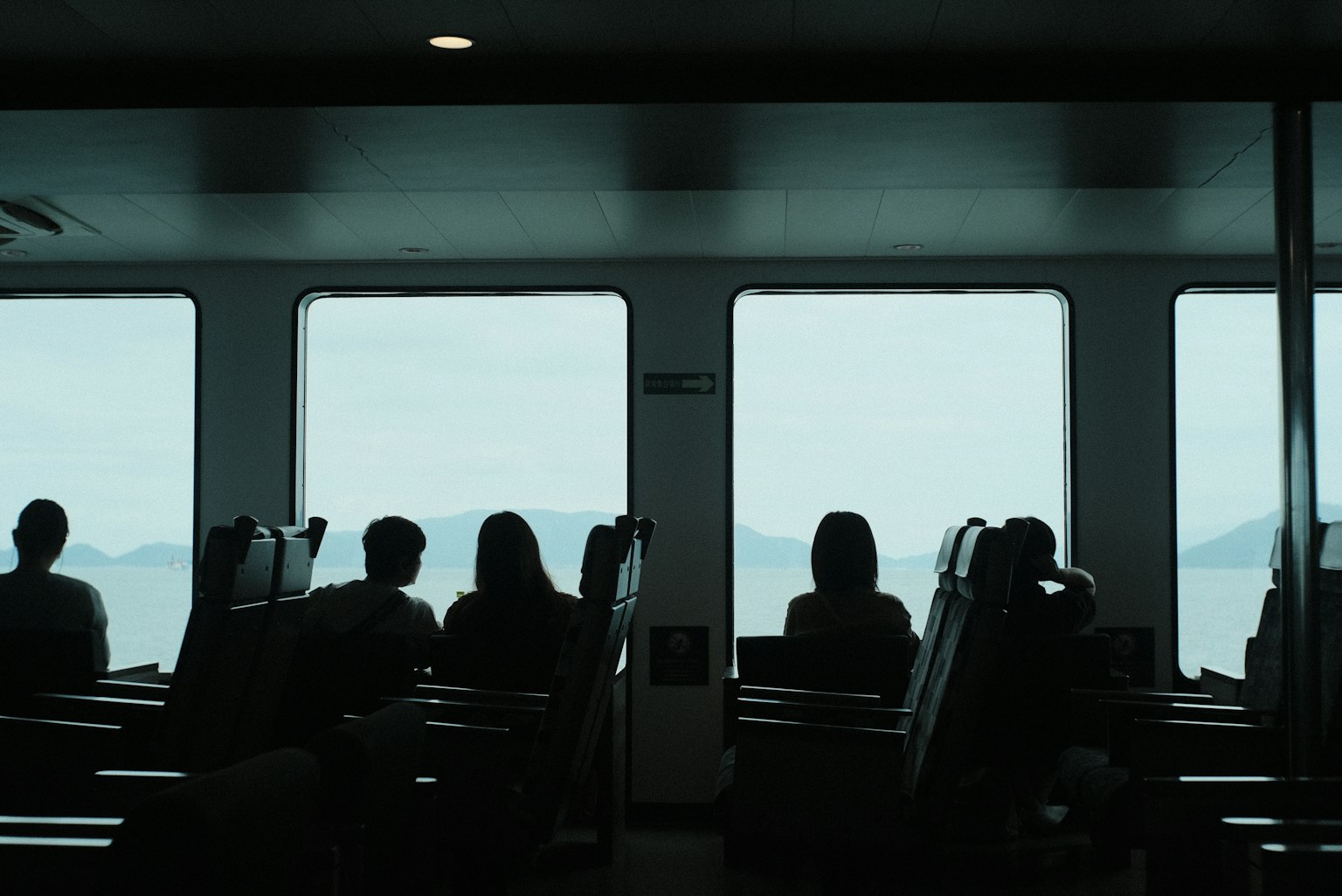 Silhouette di persone che guardano il mare e le montagne attraverso le finestre